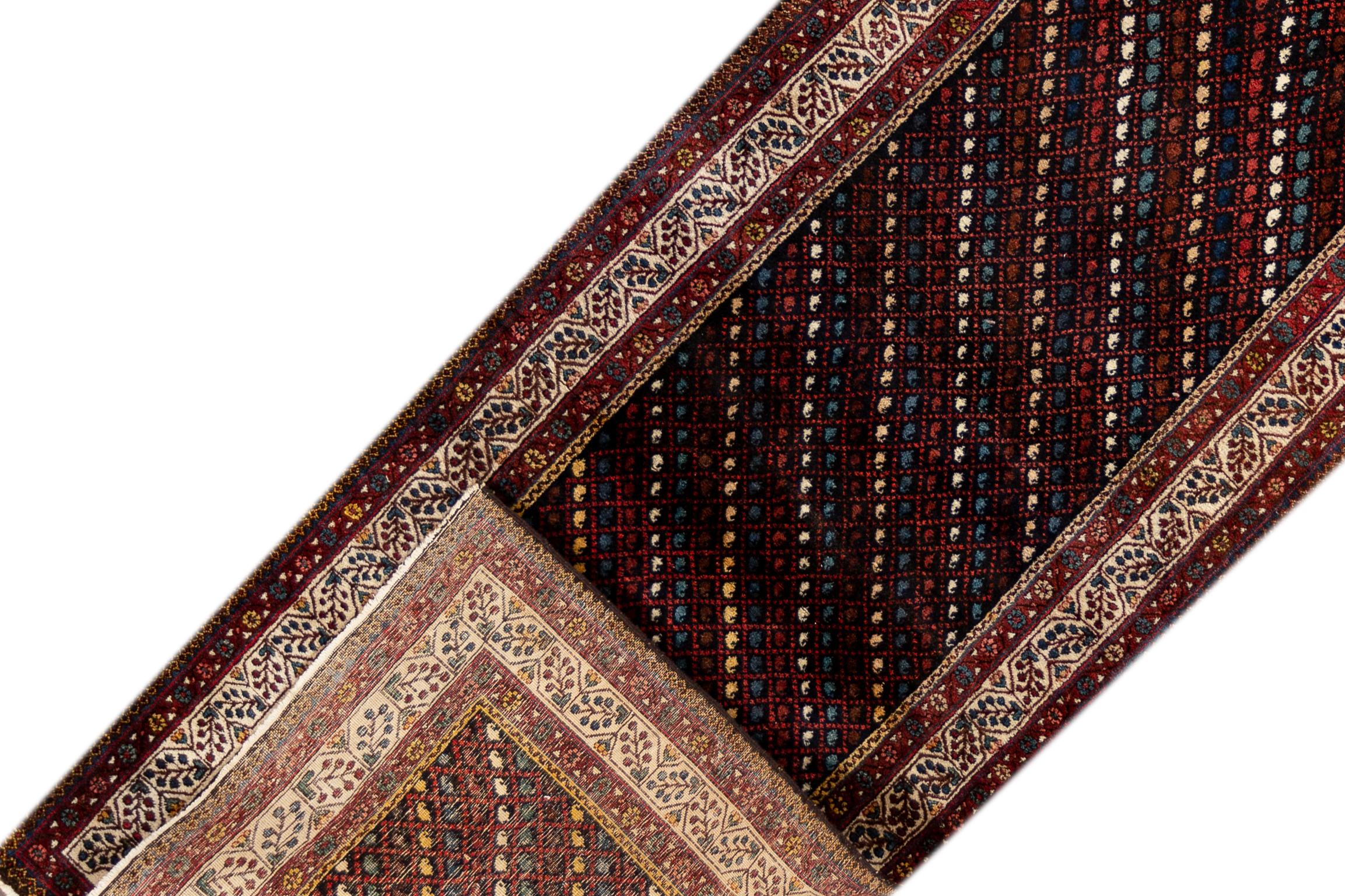A 20th century vintage Heriz runner rug with a dark red field, a striped motif and a border. This rug measures at 3'8