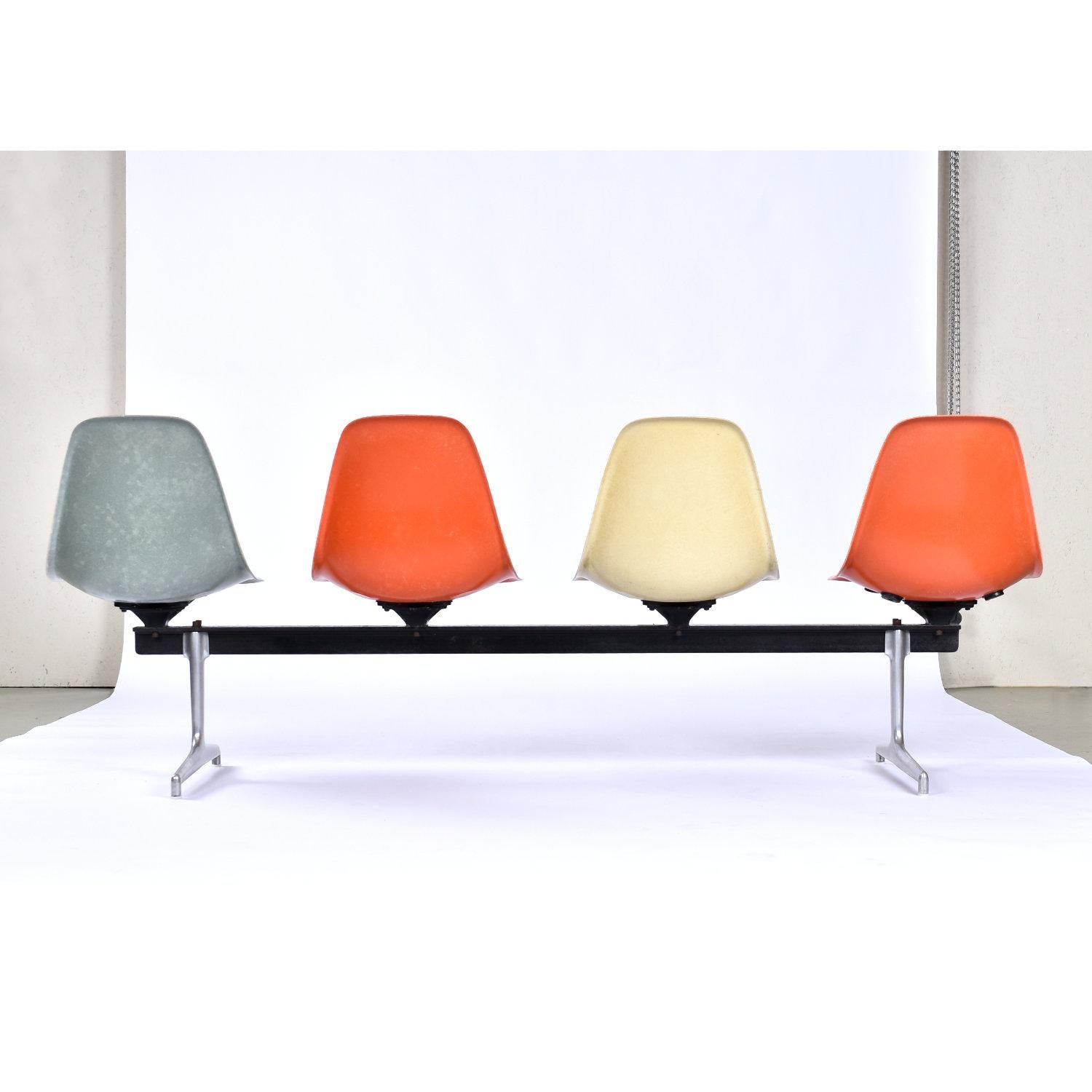 Iconic Mid-Century Modern Charles and Ray Eames for Herman Miller tandem bench. This modular system features four Eames shell chairs. I must say, this color way is particularly exciting. We love the playful orange, parchment, and light blue