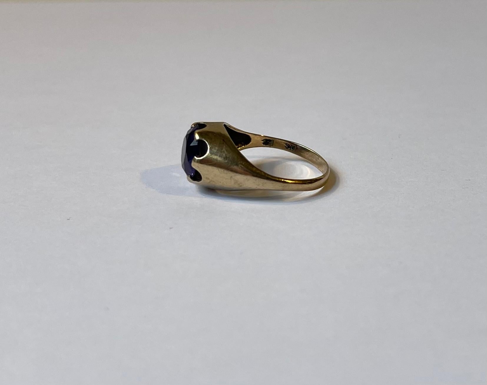 Midcentury ladies ring size 17/57 on ring measurer. Its made from solid 14 carat yellow gold and is set with a faceted dark amethyst with both blue and purple tonalities. Designed and made by Herman Siersbøl in Denmark circa 1960-70. Hallmarked: HS,