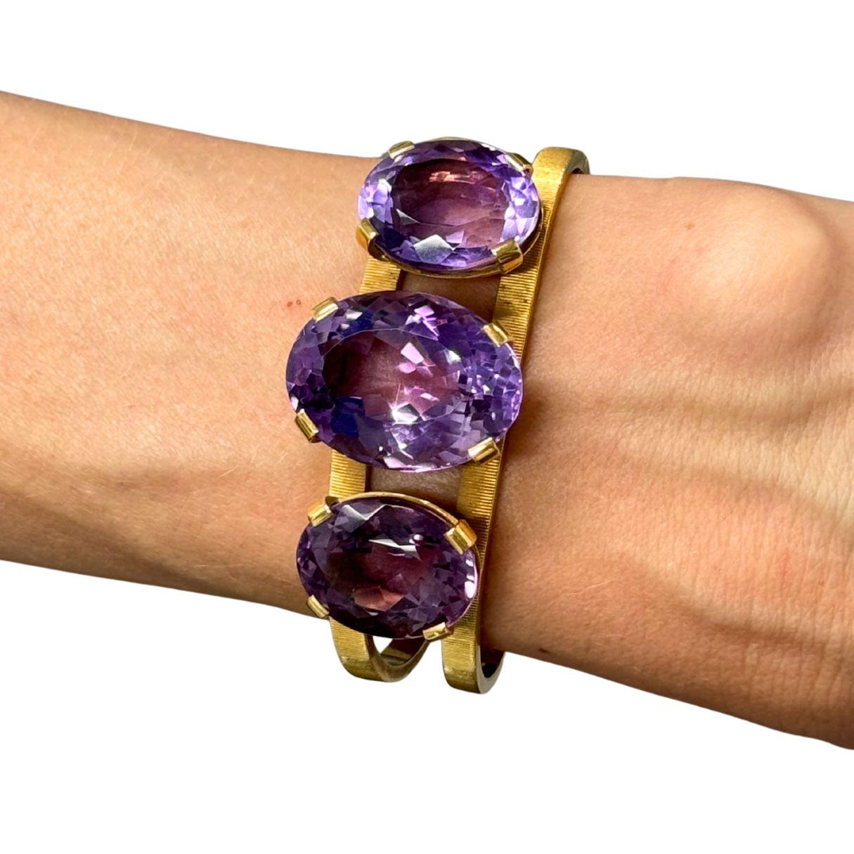 Un sorprendente bracciale vintage di Hermès realizzato in oro giallo 18 carati, con tre vivaci ametiste dal taglio ovale incastonate in modo perfettamente bilanciato. Ogni ametista irradia una profonda tonalità viola, catturando la luce attraverso
