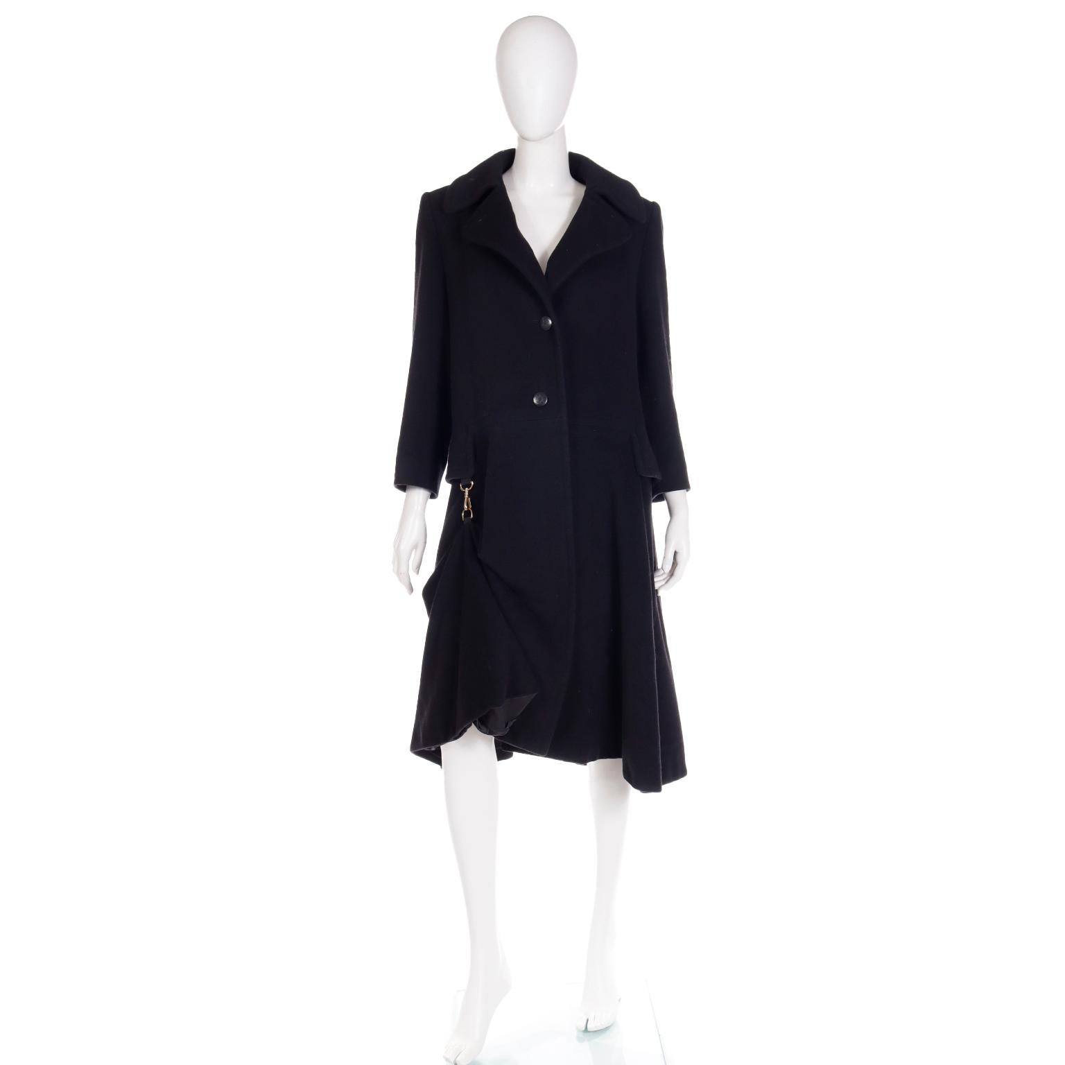 This vintage Hermes black coat is in 100% cashmere and is in such a unique style!  The coat has a fuller skirted lower portion with an optional toggle closure at one side that creates an asymmetrical hemline when attached!  The coat has a collar,