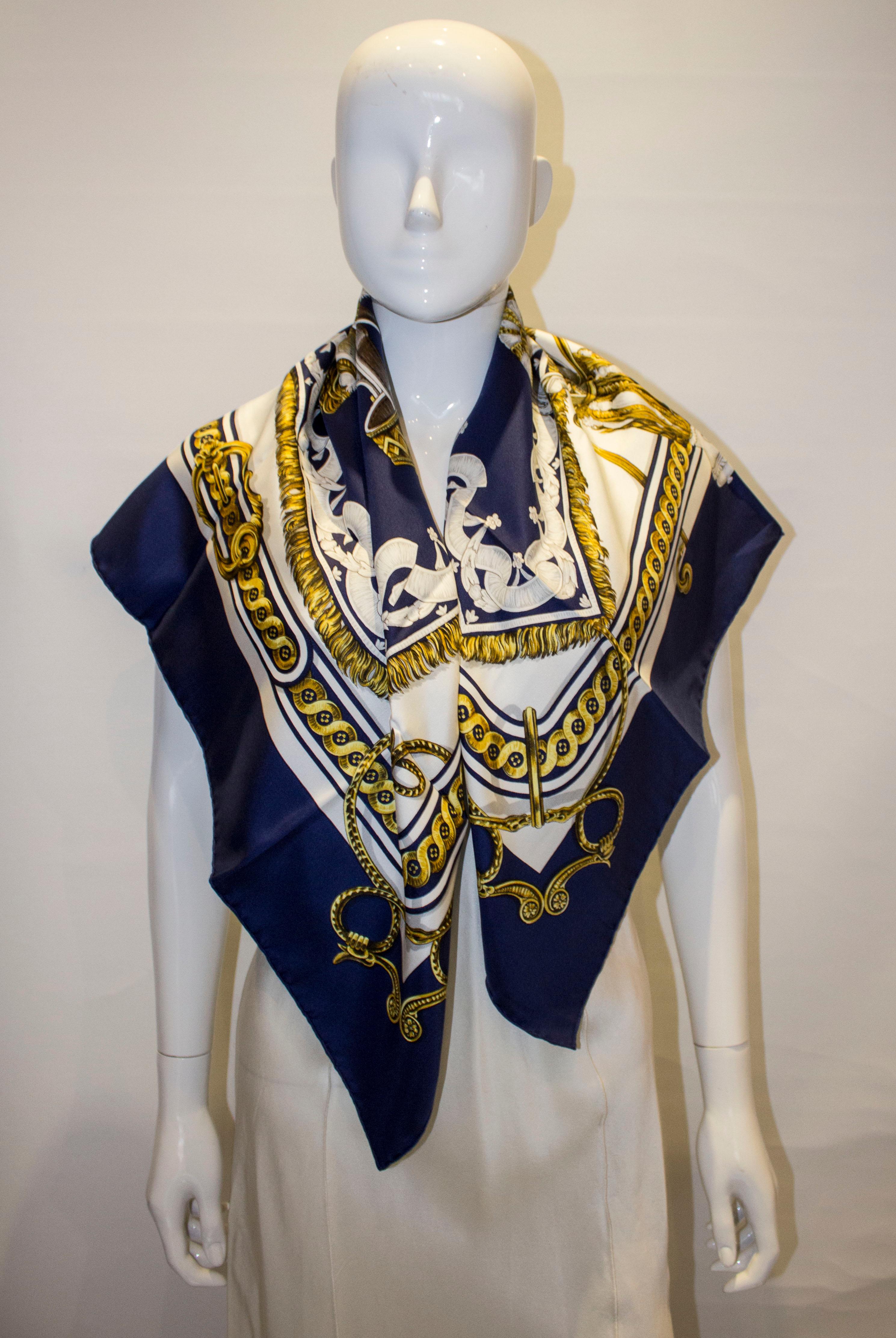 A chic and classic silk scarf  by Hermes. The design isd bride de Cour by F de la Perrierei , with a blue broder and grey , gold and white design.  
Measurement 35'' x 35''