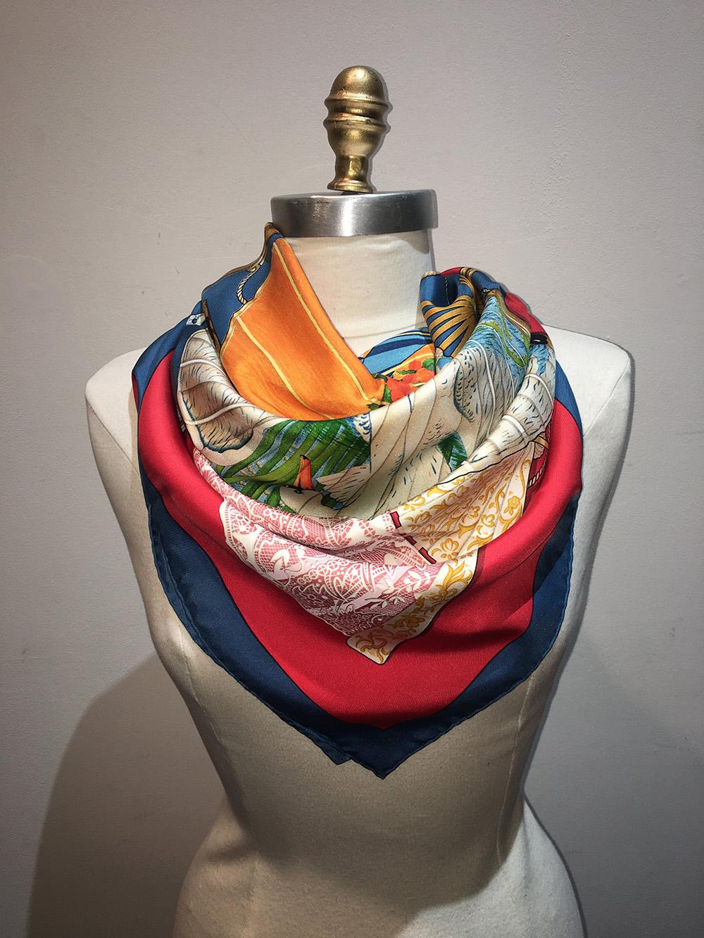 Vintage Hermes Brise de Charme Silk Scarf in Red and Navy in excellent condition. Original silk screen design c1991 by Julia Abadie features an assortment of antique fans in lace, peacock, horse, swan and floral prints over a red background
