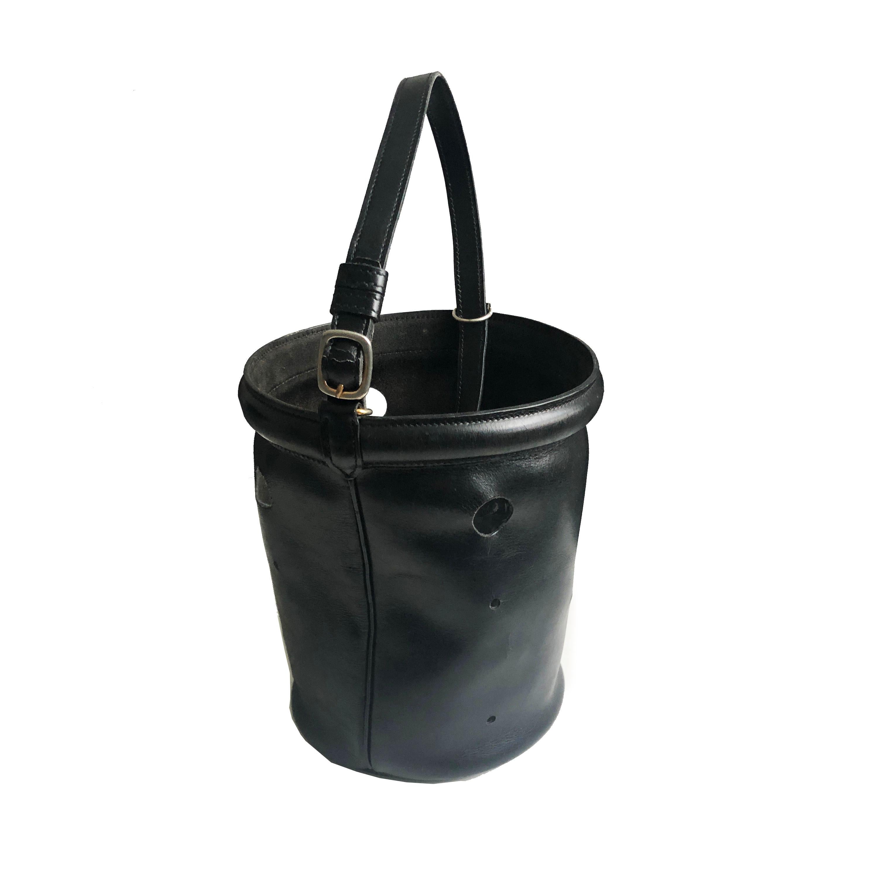 Authentic, preowned, vintage Hermes Bucket Feed Bag Seau Mangeoire PM in black box leather, likely made in the late 50s.  A unique vintage bag with strategically placed holes, which enable one to decorate with their favorite carre or scarf, as we've