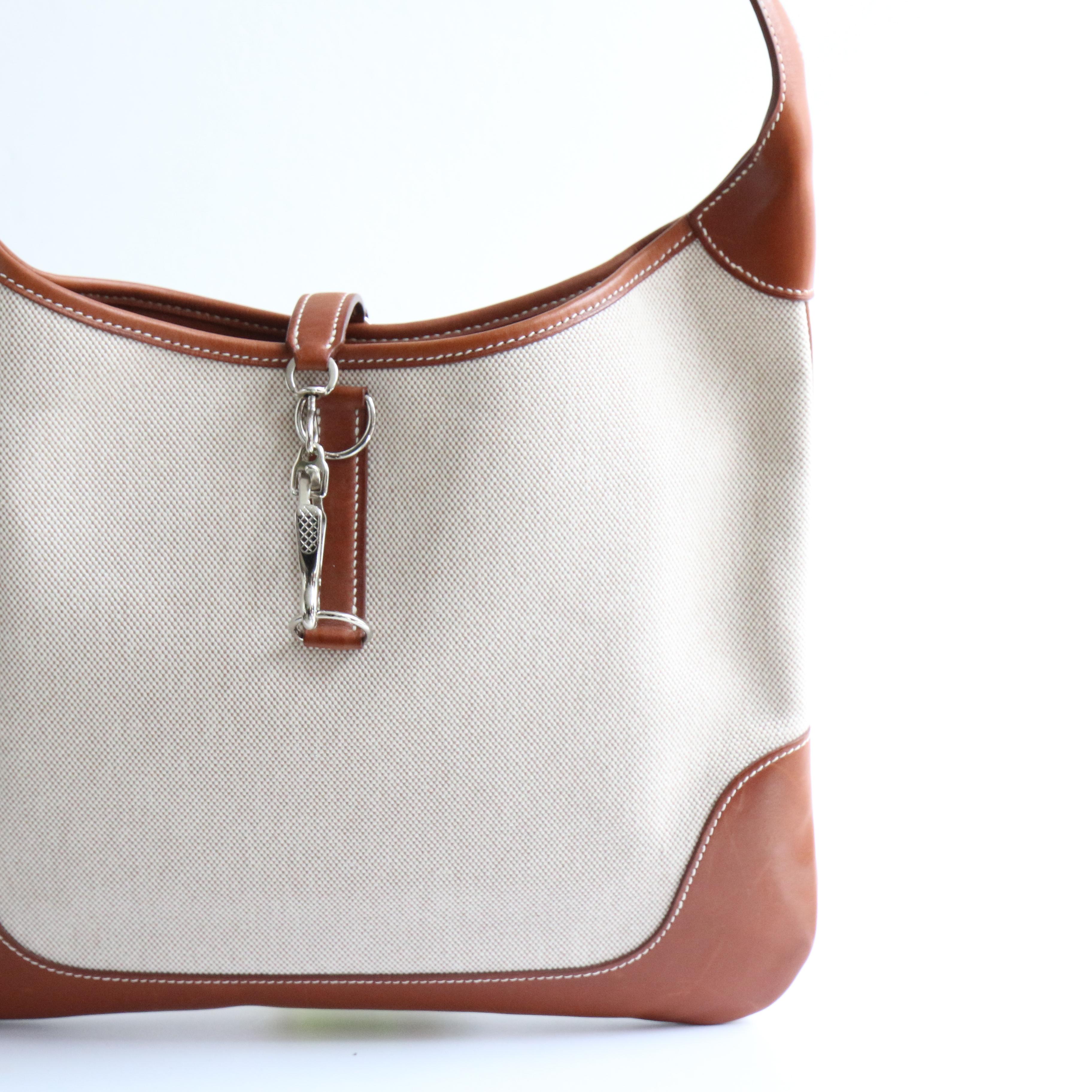 This wonderful canvas and tan coloured leather Hermès shoulder bag, accented by white stitching and iconic silver hardware is the perfect piece to elevate your everyday wardrobe.

Her adjustable tan leather shoulder strap, frames the saddle cut of