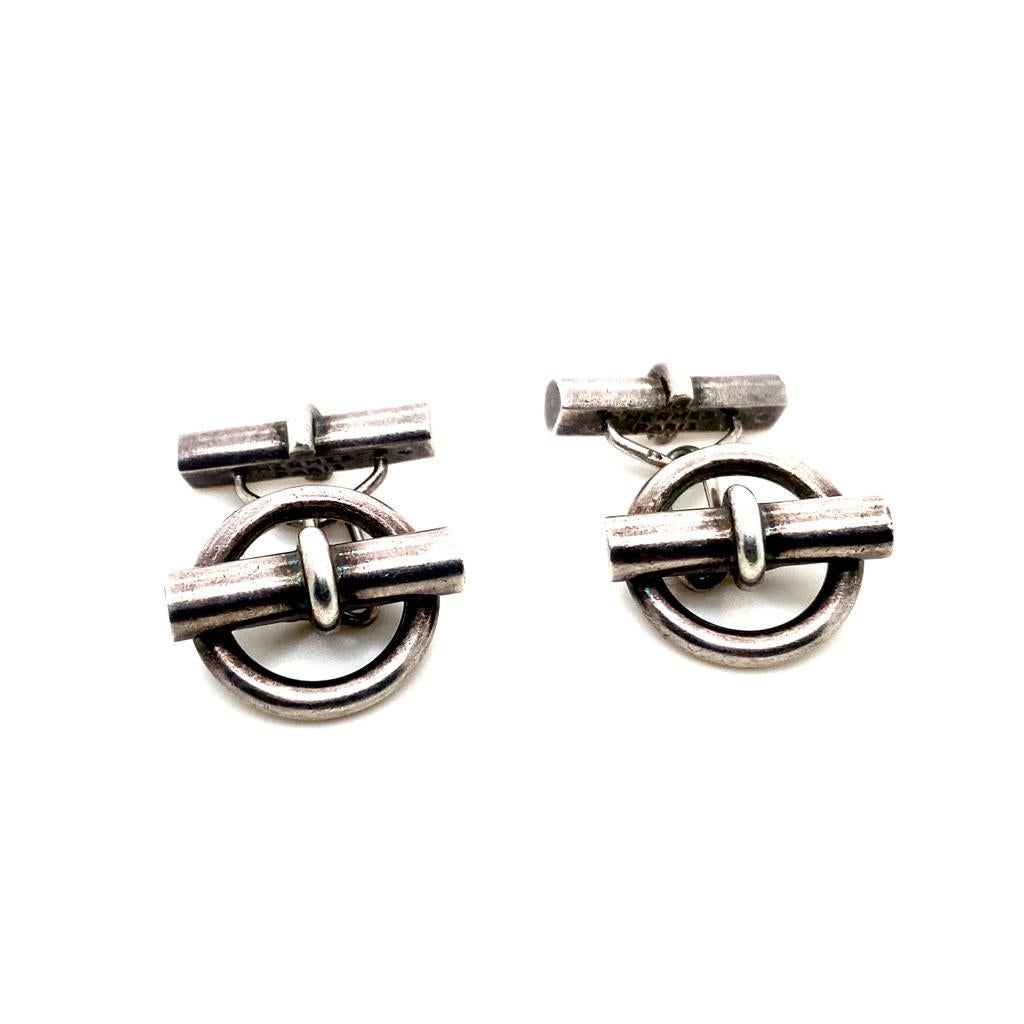 A pair of vintage Hermès Chaîne d'Ancre cufflinks, circa 1950.

Each cufflink is based on the fastening from the iconic Hermès Chaîne d'Ancre bracelet, with one silver baton attached to a flattened oval link leading to a circular terminal, with a