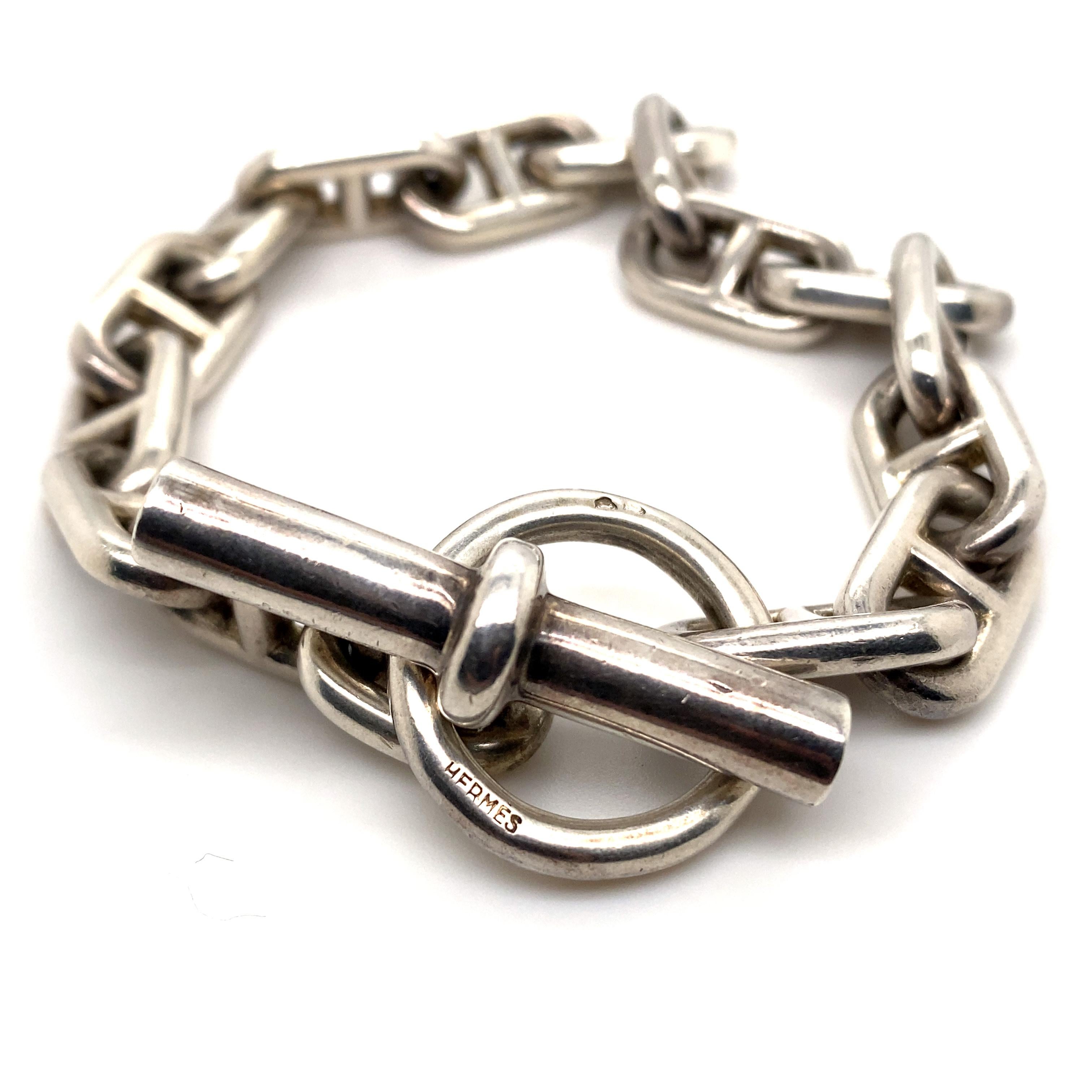 An Hermès Chaîne d'Ancre silver bracelet circa 1950.

This iconic Hermès bracelet is composed of silver oval links each with a bar spacer, to a circular or baton terminal, with a classic T-bar fitting. 
Signed HERMES to the larger circular