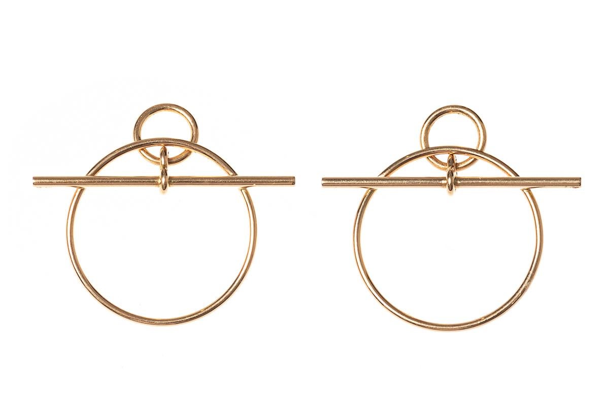 A pair of 18 karat yellow gold earrings of abstract design with a large outer hoop, a smaller hoop and a cross bar. Signed Hermès of Paris and numbered 12 C0122 together with a 750 mark denoting 18 karat gold. In original case.
Cross bar length is