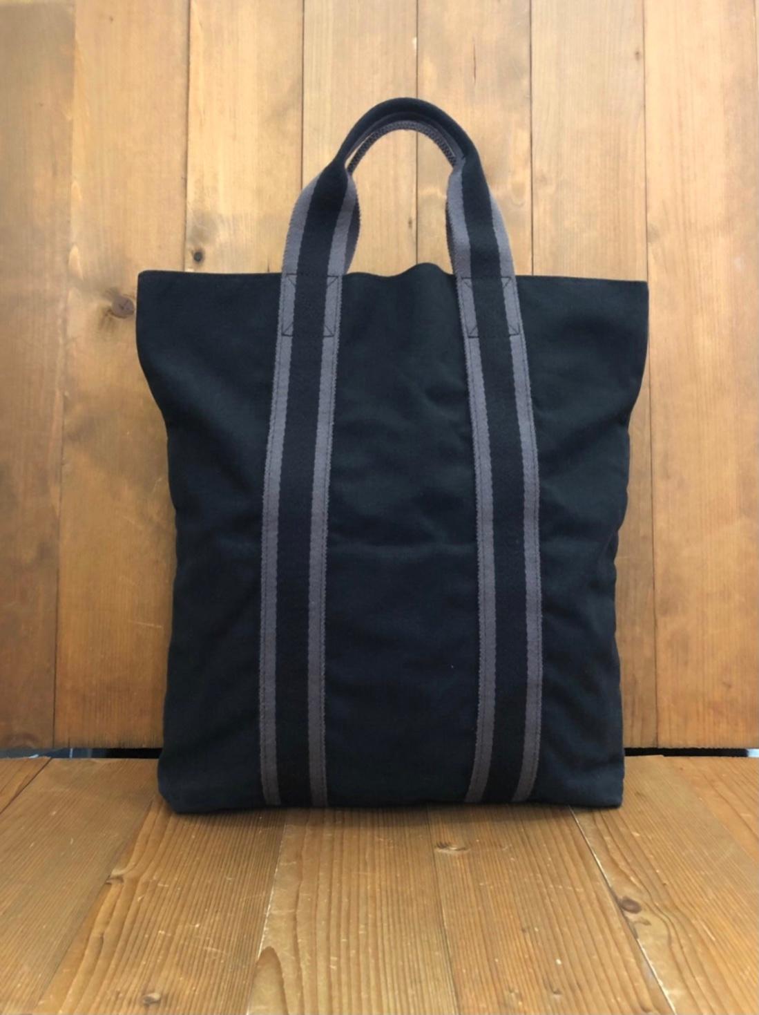 Vintage HERMES Fourre Tout in navy colored cotton with gray stripe featuring three exterior open pockets and one interior open pocket. Measures approximately  14 (top) 12 (bottom) x 15 x 2.5 inches Handle drop 4 inches. 

Condition - Some signs of