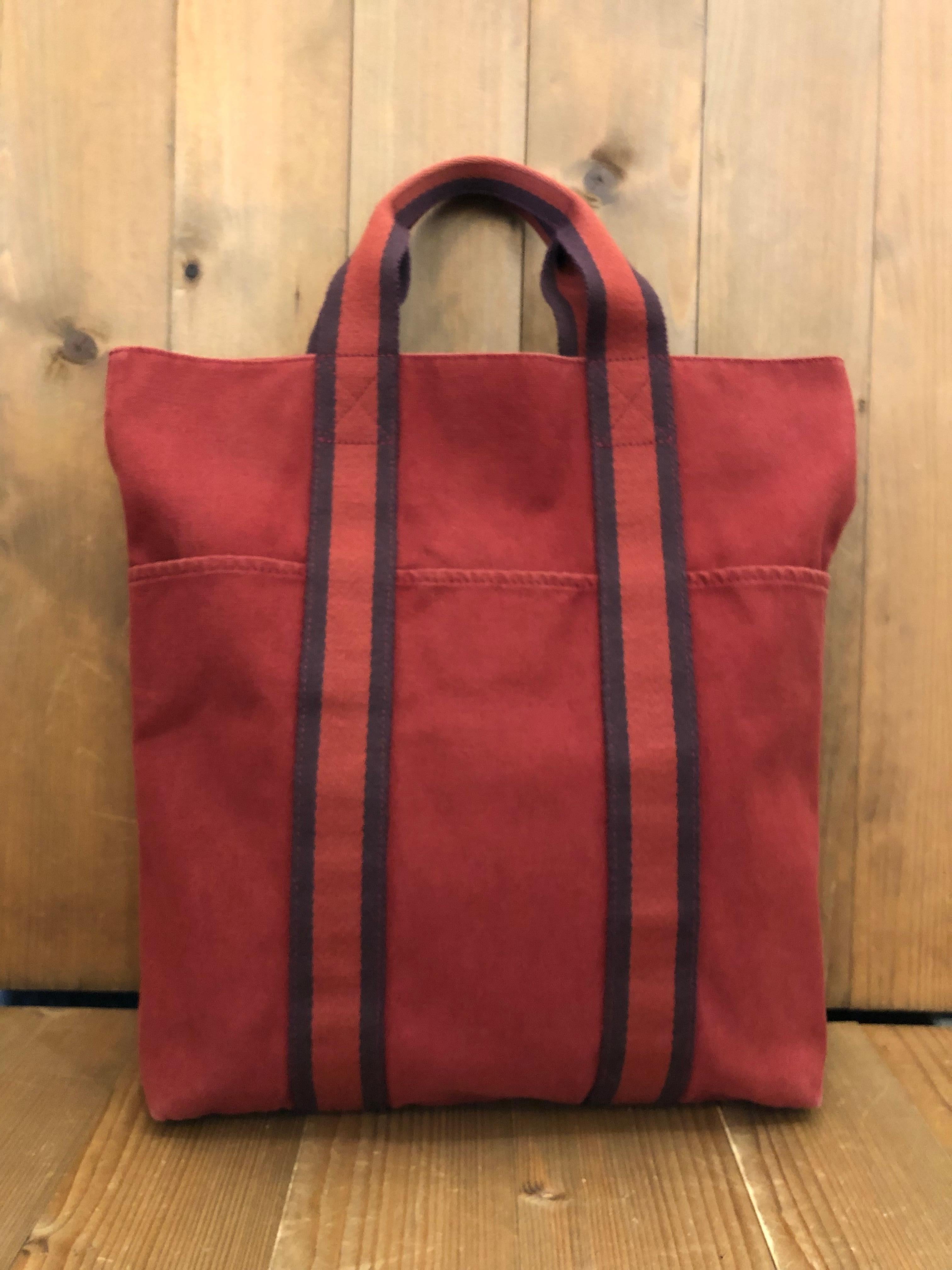 Vintage HERMES Fourre Tout in orange colored cotton featuring three exterior open pockets and one interior open pocket. Measures approximately  14 (top) 12 (bottom) x 15 x 2.5 inches Drop 4 inches. 

Condition - Some signs of wear consistent with