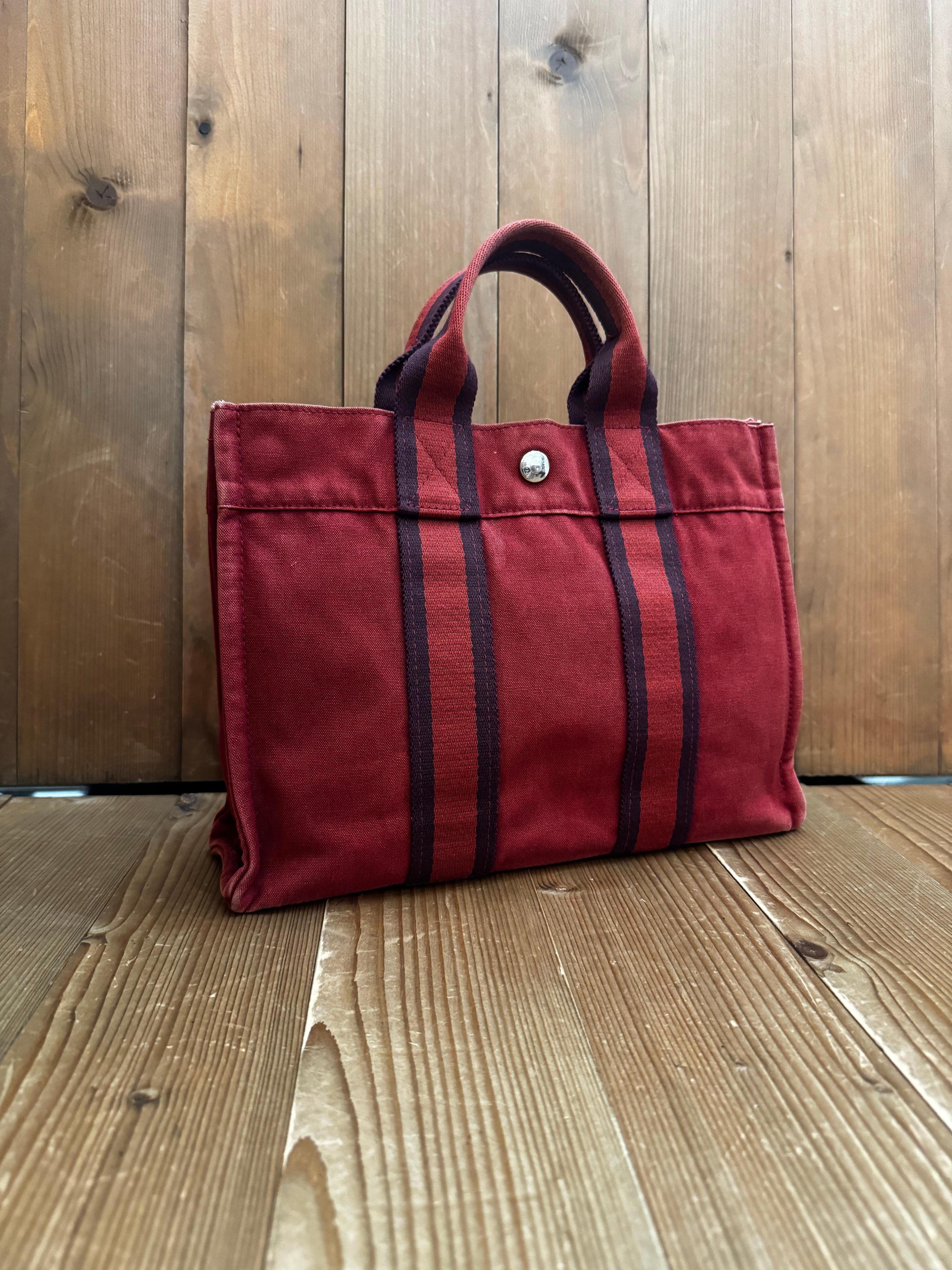 This vintage HERMES Fourre Tout PM tote is crafted of cotton in orange featuring sturdy handles of stripe canvas. Wide top with snap closure opens to an interior of the same cotton fabric featuring a zippered pocket. This is a sophisticated tote