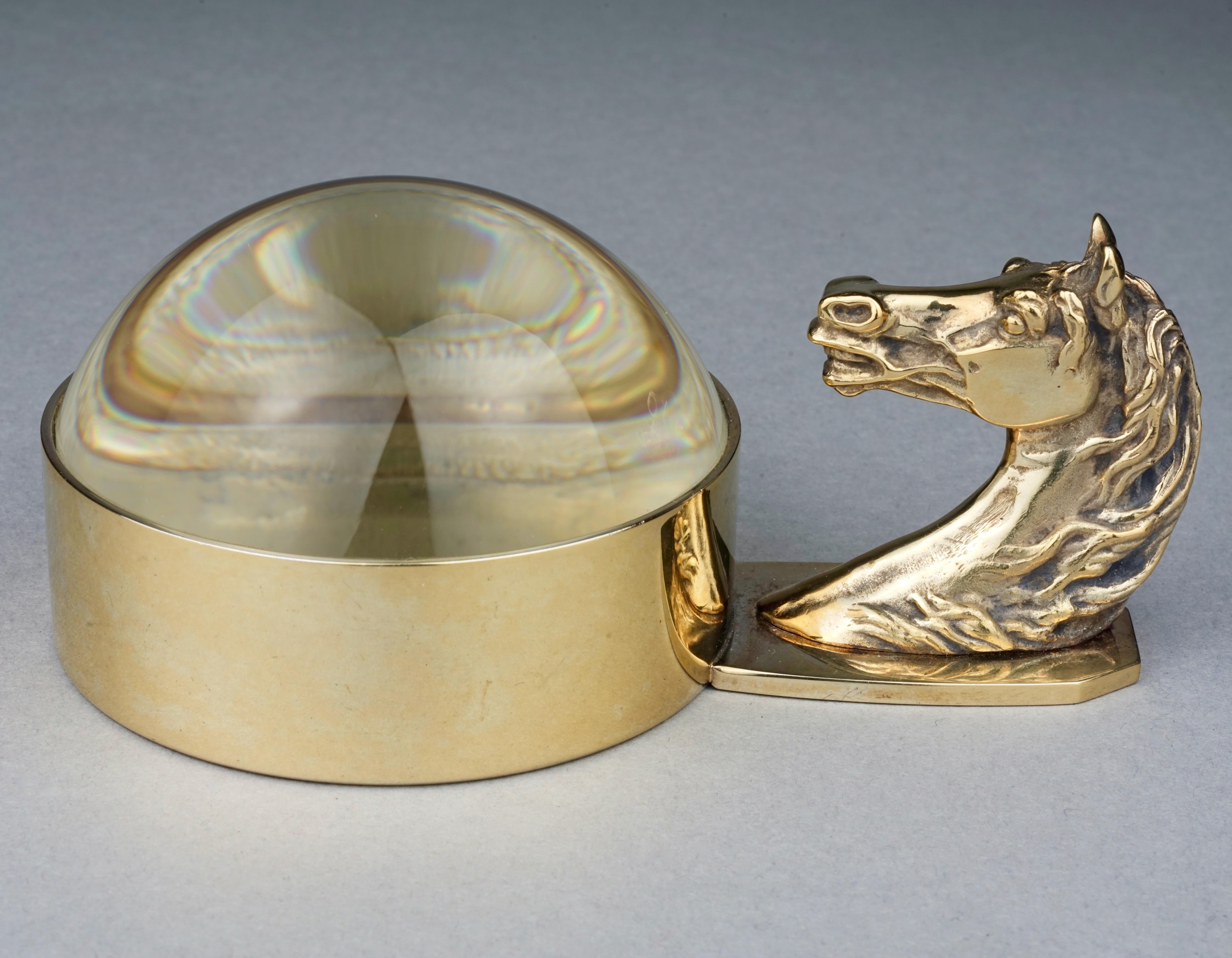 Vintage HERMES Gold Horse Head Art Deco Paperweight Magnifying Glass

Measurements:
Horse Head: 2.12 inches (5.4 cm)
Width: 5.11 inches (13 cm)
Diameter: 3.15 inches (8 cm)

Features:
- 100% Authentic HERMES.
- Horse head handle with dome magnifying