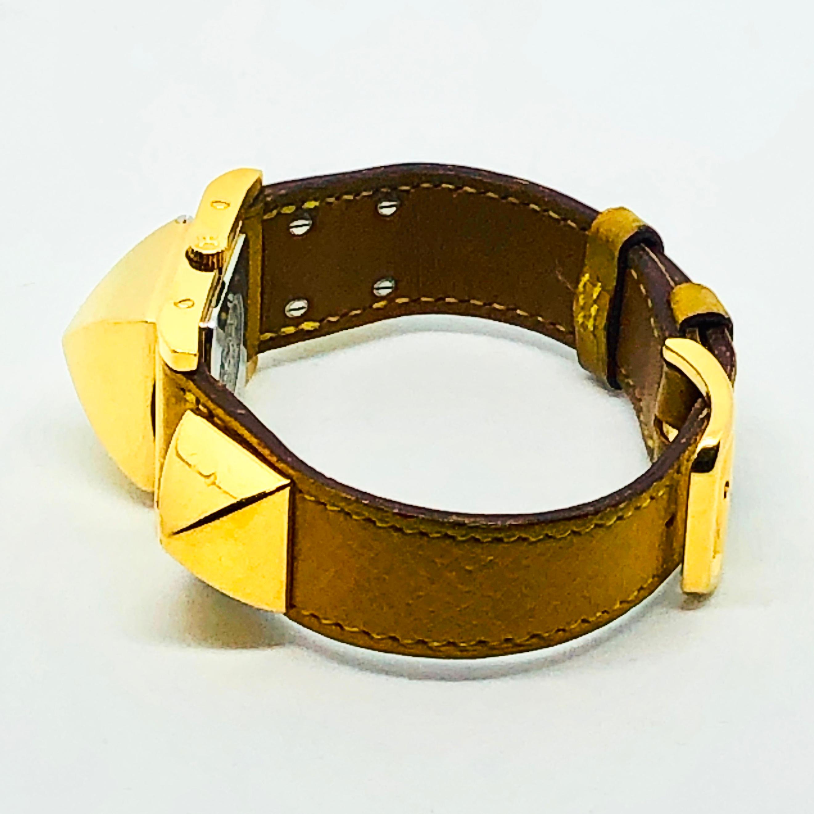 Hermes Ladies Gold Plated stainless steel Medor quartz Wristwatch with a yellow leather watchband.  This iconic watch is recognized the world over with the embellishment of pyramid shaped decorations as Hermes.

This wristwatch does double-duty as a