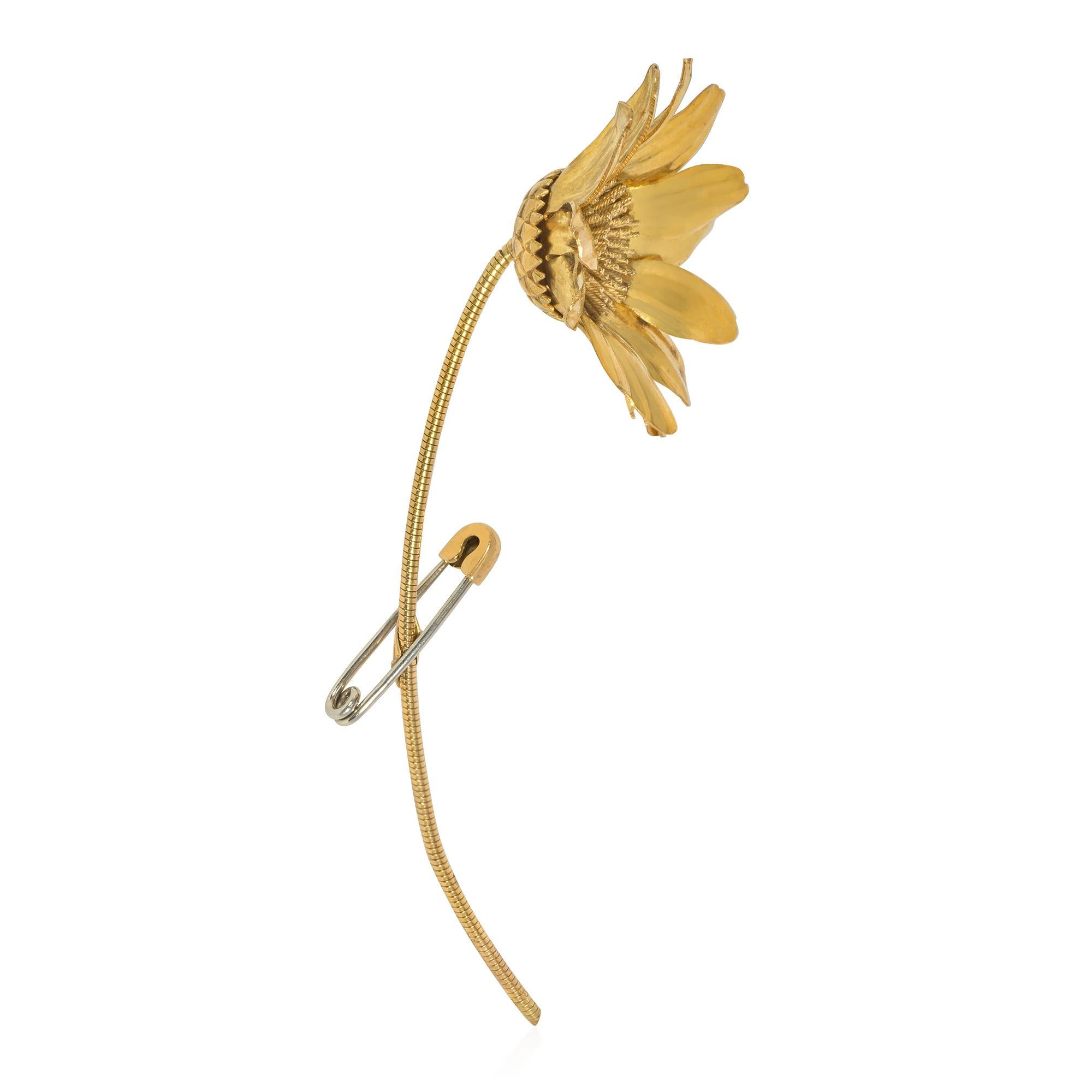 A mid-century gold statement brooch designed as a safety pinned daisy with a central disk of rope twist gold wires, engraved sepal, and a gas pipe-like stem, in 18k. Hermès, Paris. #39604.