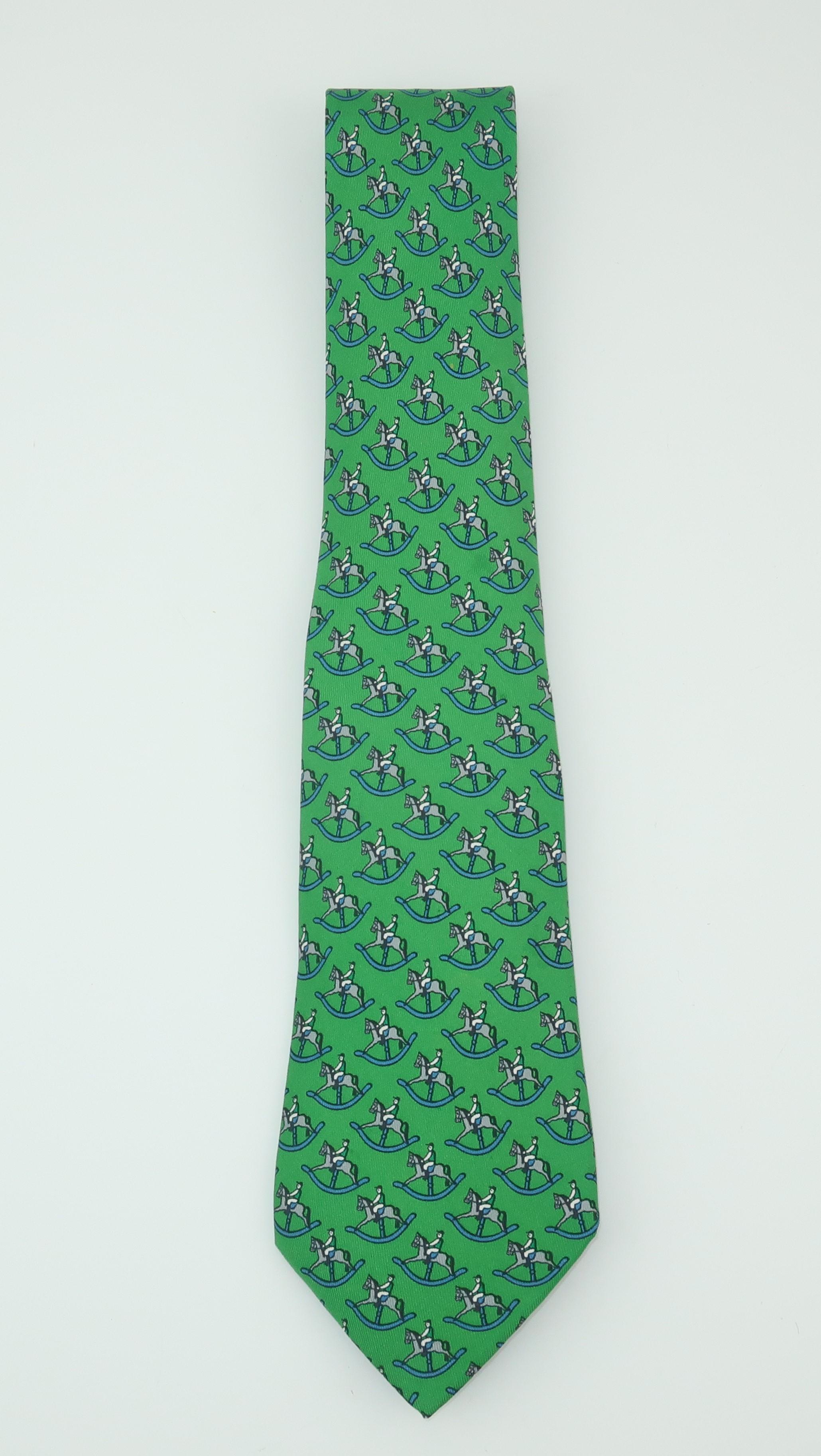 A vintage Hermes menswear French green silk necktie with a whimsical design featuring jockeys and rocking horses in shades of blue, gray, white and black. It is beautifully made with the quality one would expect from Hermes.  Good previously owned