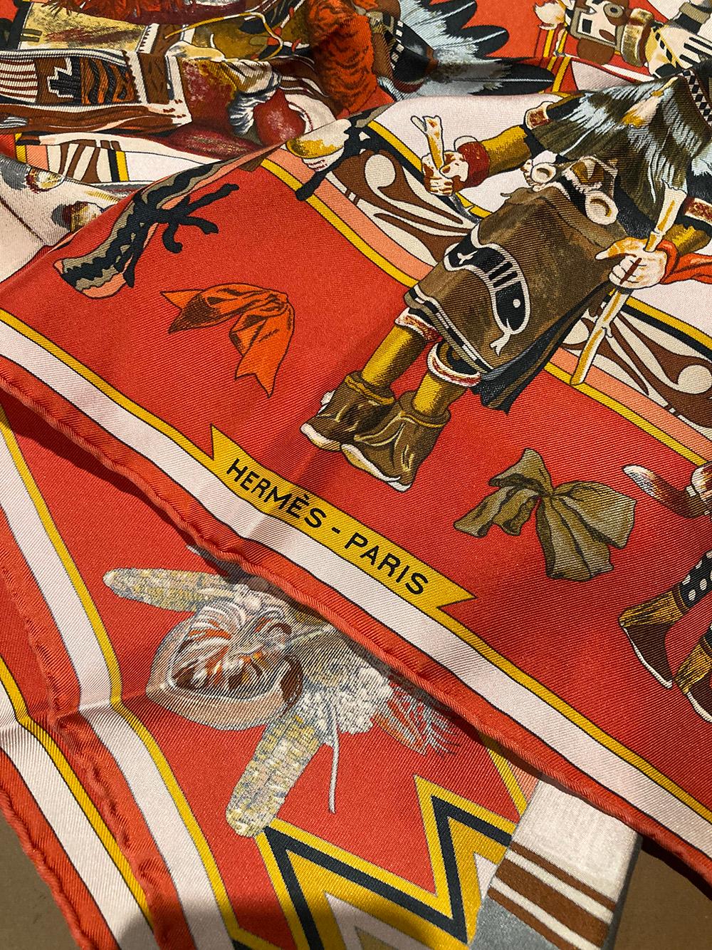 RARE Hermes Vintage Kachinas Silk Scarf in excellent condition. Original silk screen design c1992 by Kermit Oliver features various multicolor native american chiefs and people in traditional dress over a multi tonal coral background with coral,