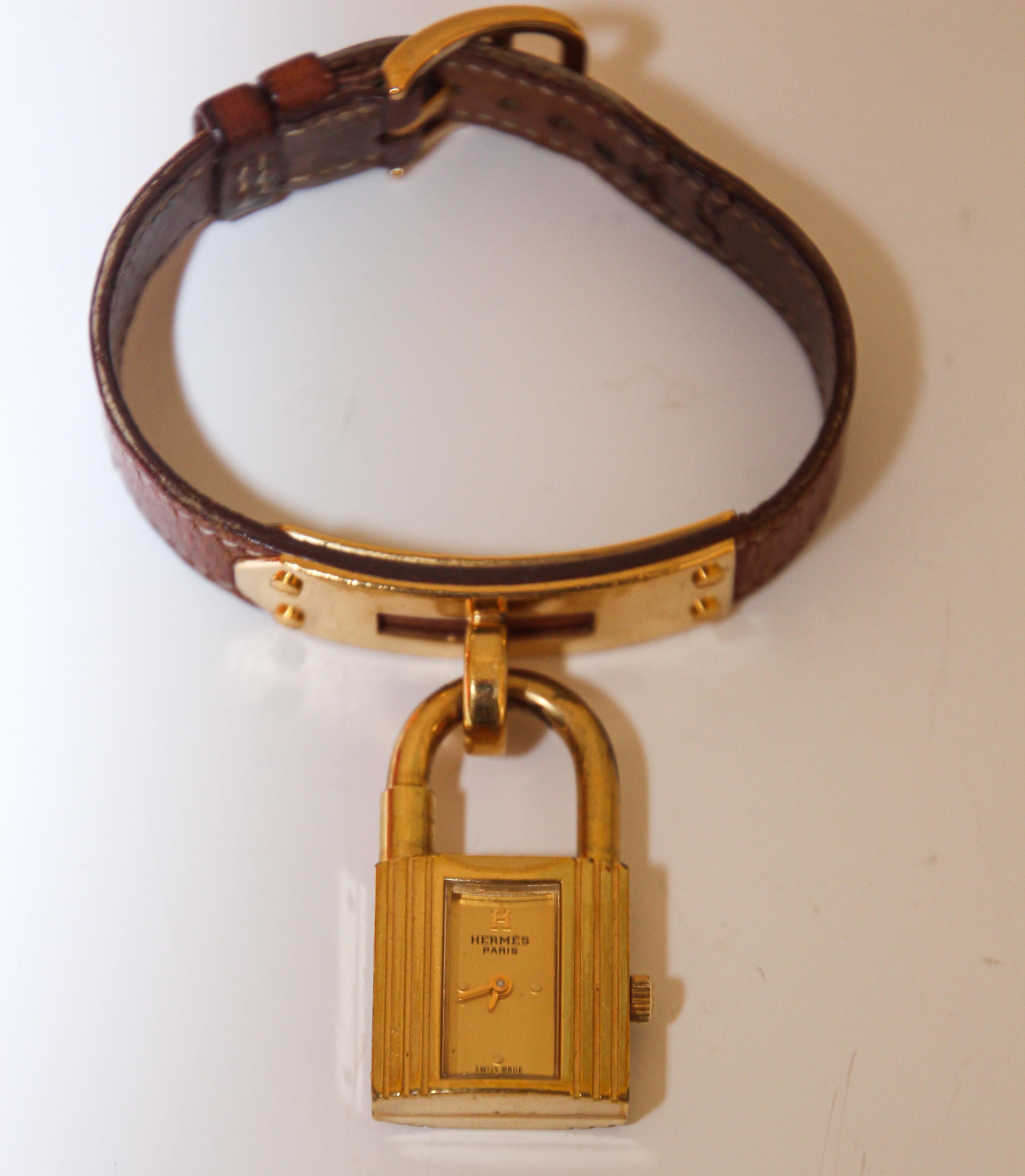 Vintage Hermes Kelly Watch.
1989 Hermes tan leather Kelly Watch gold plated.
Removable gold plated lock charm watch which dangles from a gold-plated base on the strap.
Hermes Kelly watch, stamped circle T from 1980. 
Swiss made, signed push/pull