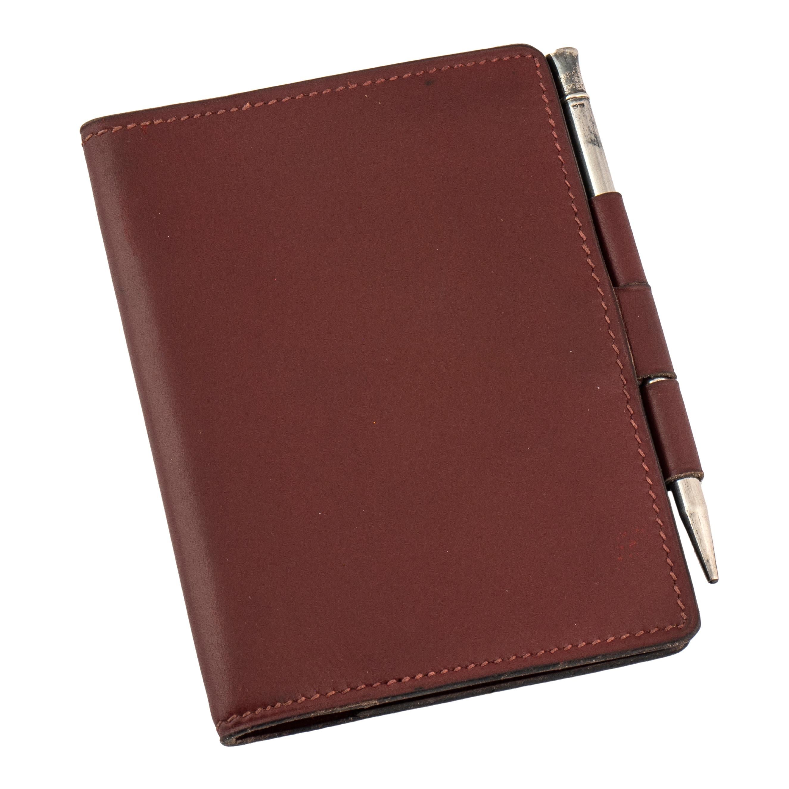 Beautiful vintage Hermès mini notebook agenda cover tooled out of the classic burgundy leather associated with the iconic Parisian luxury brand, with stiched borders and original silver pencil holder.  The leather stamped Hermès Paris, the pencil