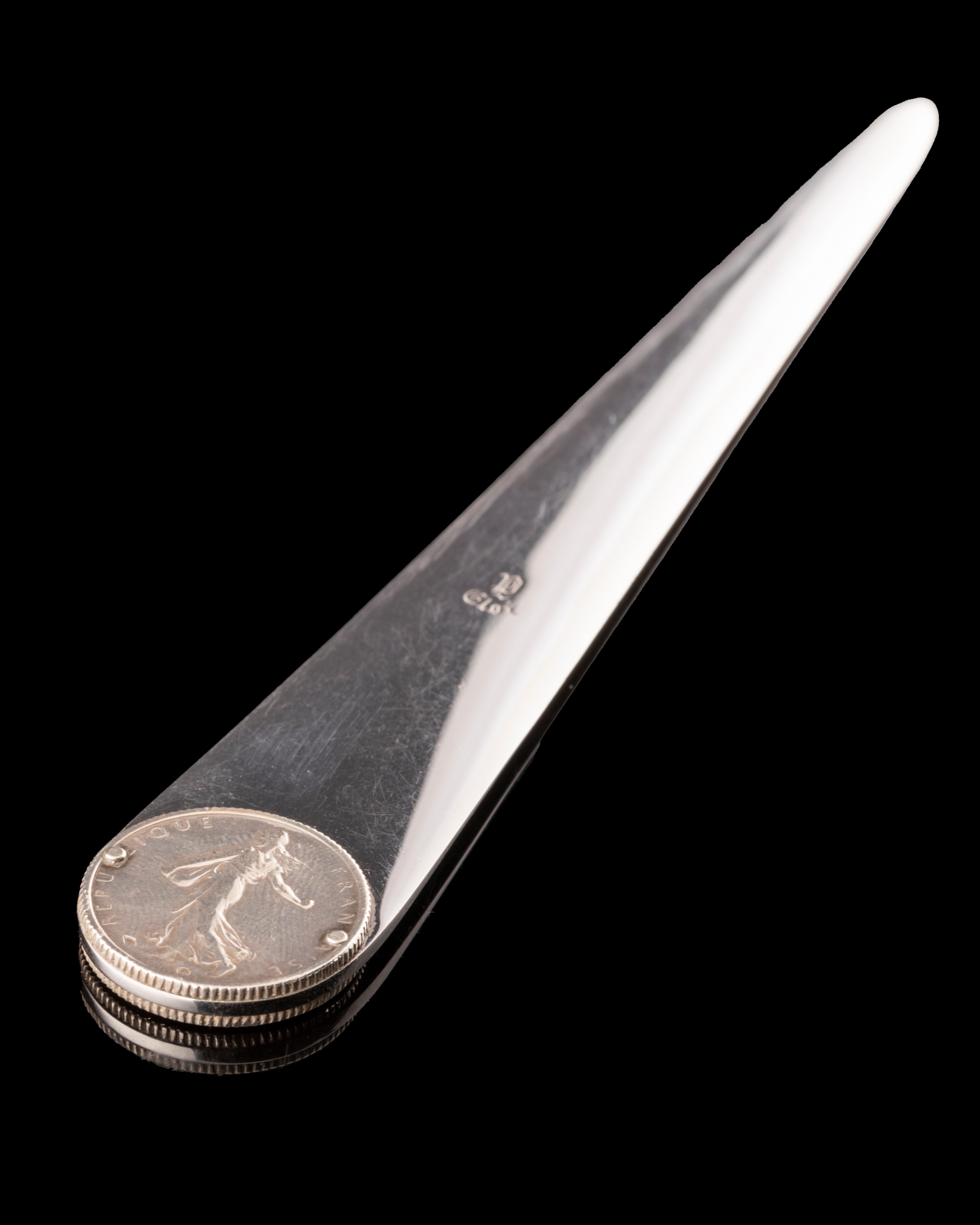 Step into a world of refined elegance with the 80's Vintage Hermès Letter Opener. Crafted with the radiant gleam of metal argenté, this exquisite piece showcases meticulous detailing and two integrated coins. A symbol of timeless grace, it embodies