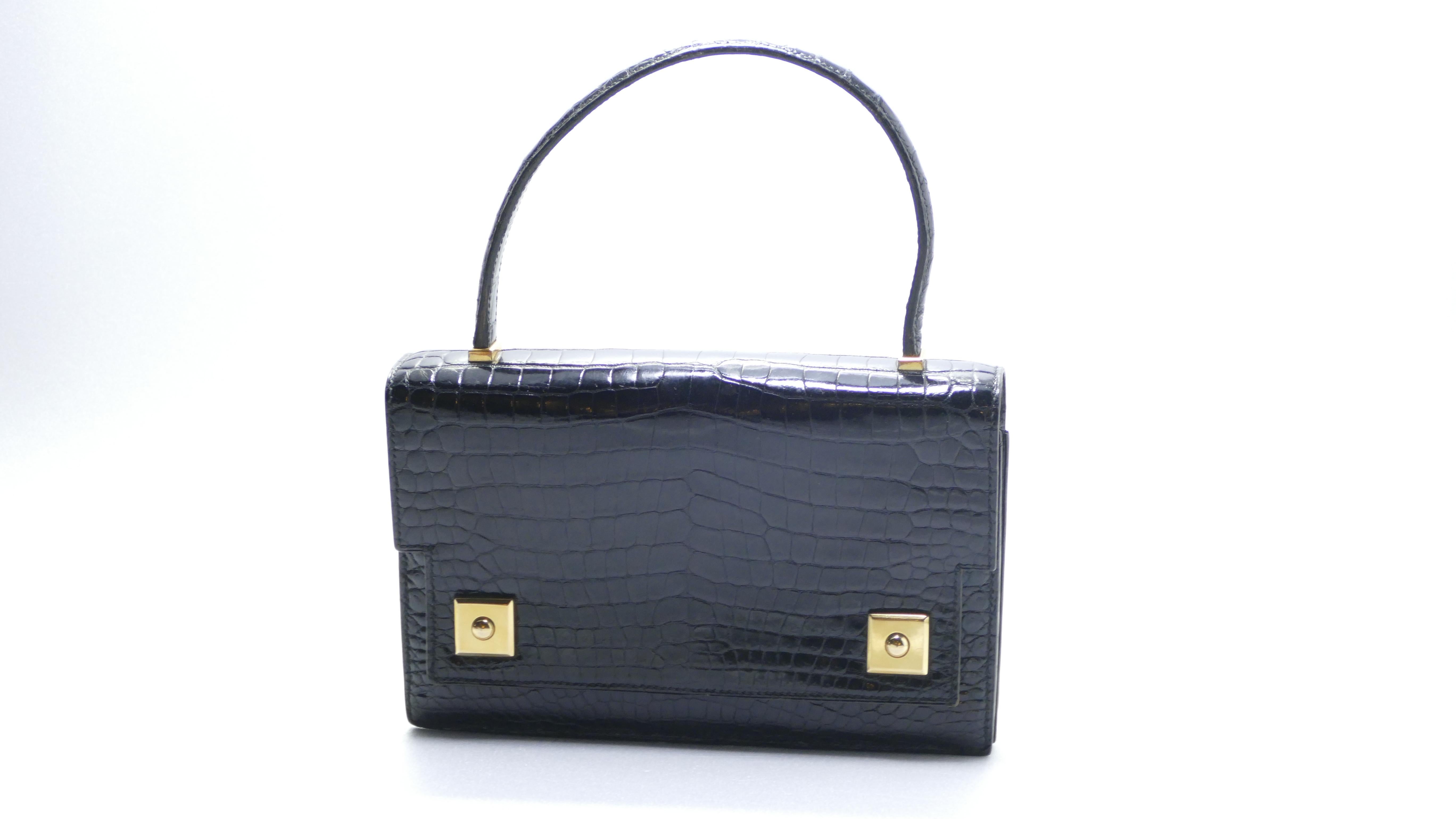 This rare Hermes Piano handbag is crafted from black Porosus crocodile, features crocodile top handle, frontal flap, and gold hardware. Its magnetic peg-in-hole closures open to a Noir black Agneau leather interior with dual compartments, flap