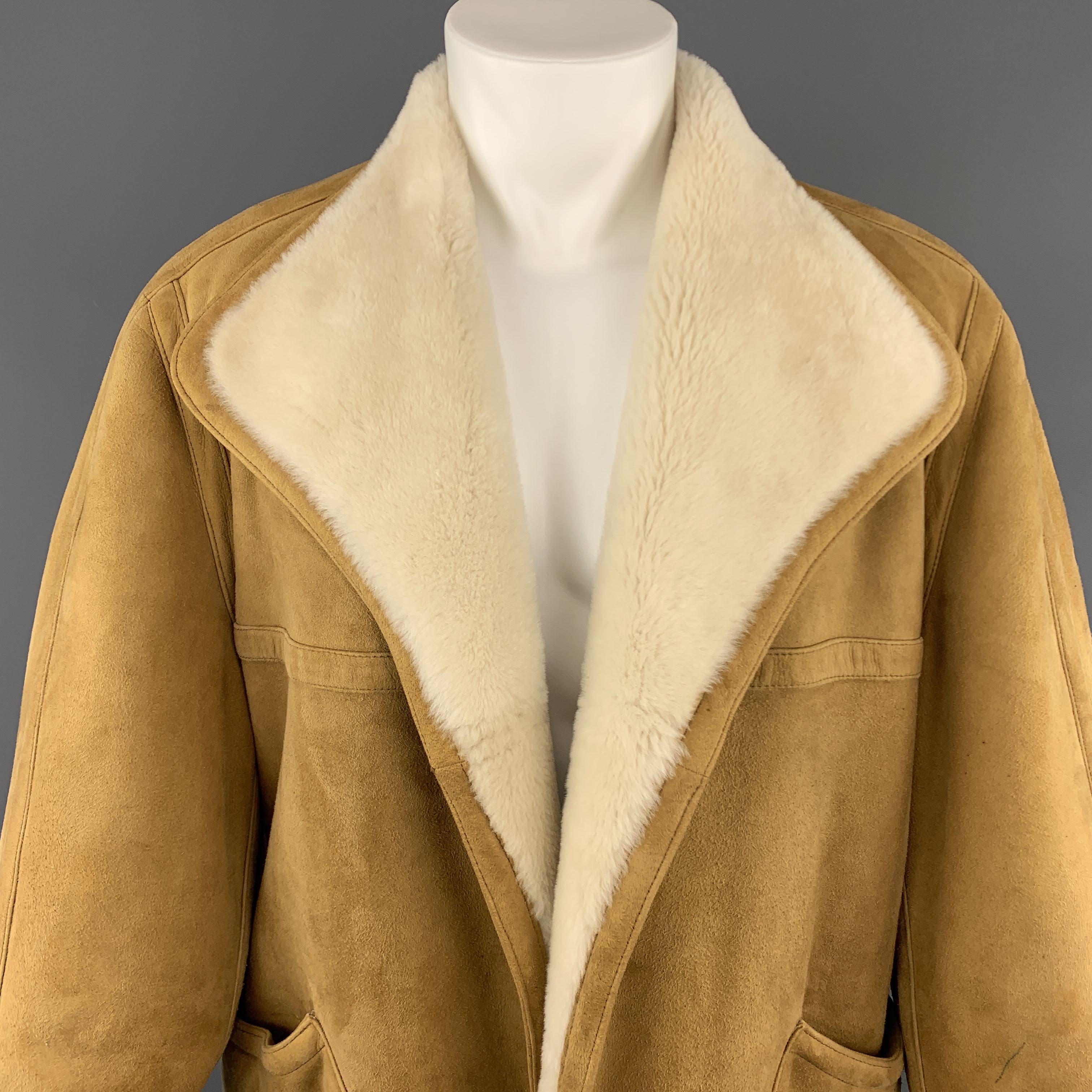 Vintage HERMES over coat comes in golden tan suede shearling with full cream trimmed fur interior and features a wide pointed collar, open front, and oversized patch pockets. Pen mark on sleeve. As-is. Otherwise excellent condition. Made in France.
