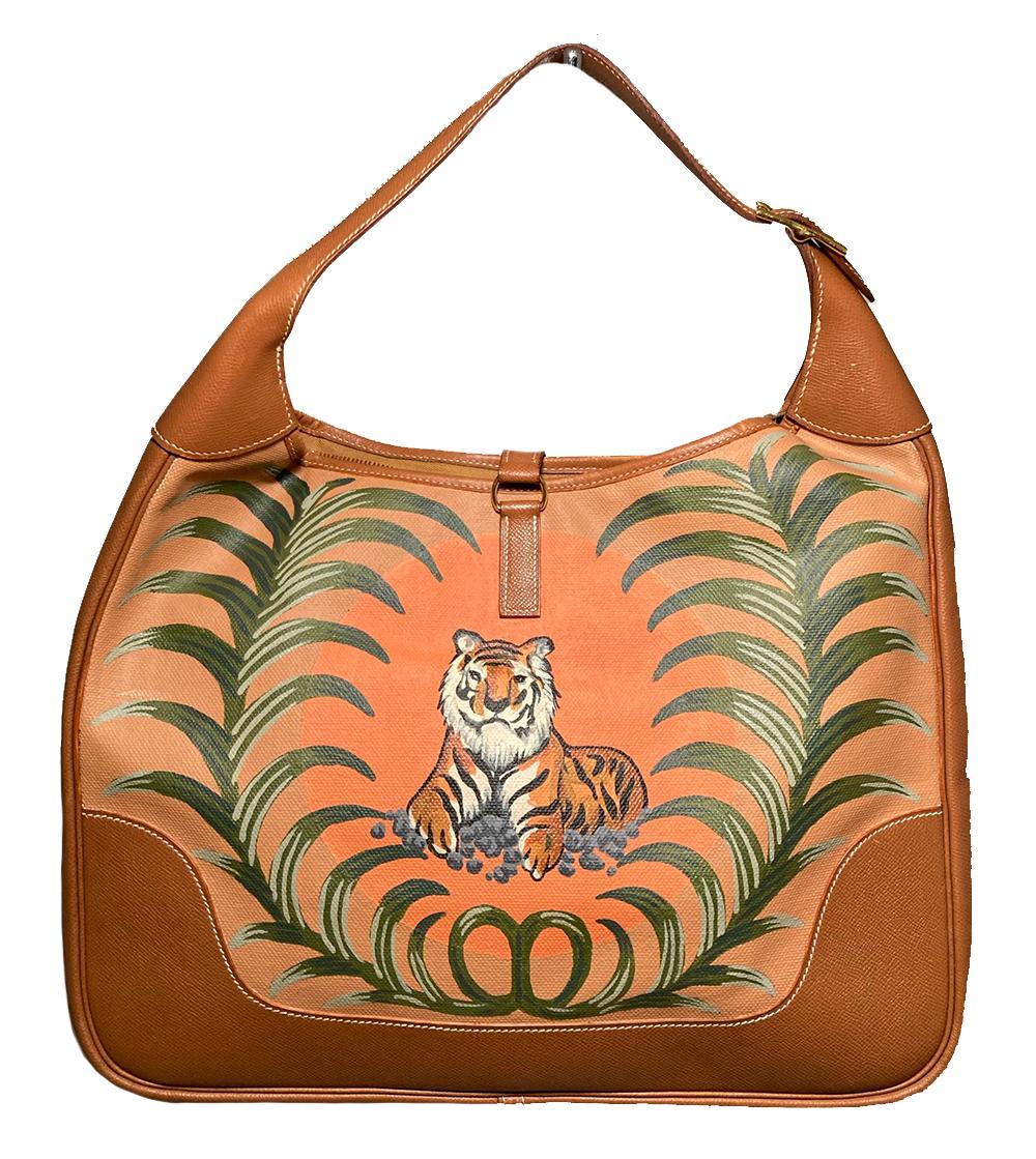 Vintage Hermes Trim Bag with Hand Painted Tiger in very good condition. Tan veau graine lisse leather and matching canvas exterior with hand painted tiger design centered in a tropical leaf print. Top zip closure opens to a beige canvas and tan