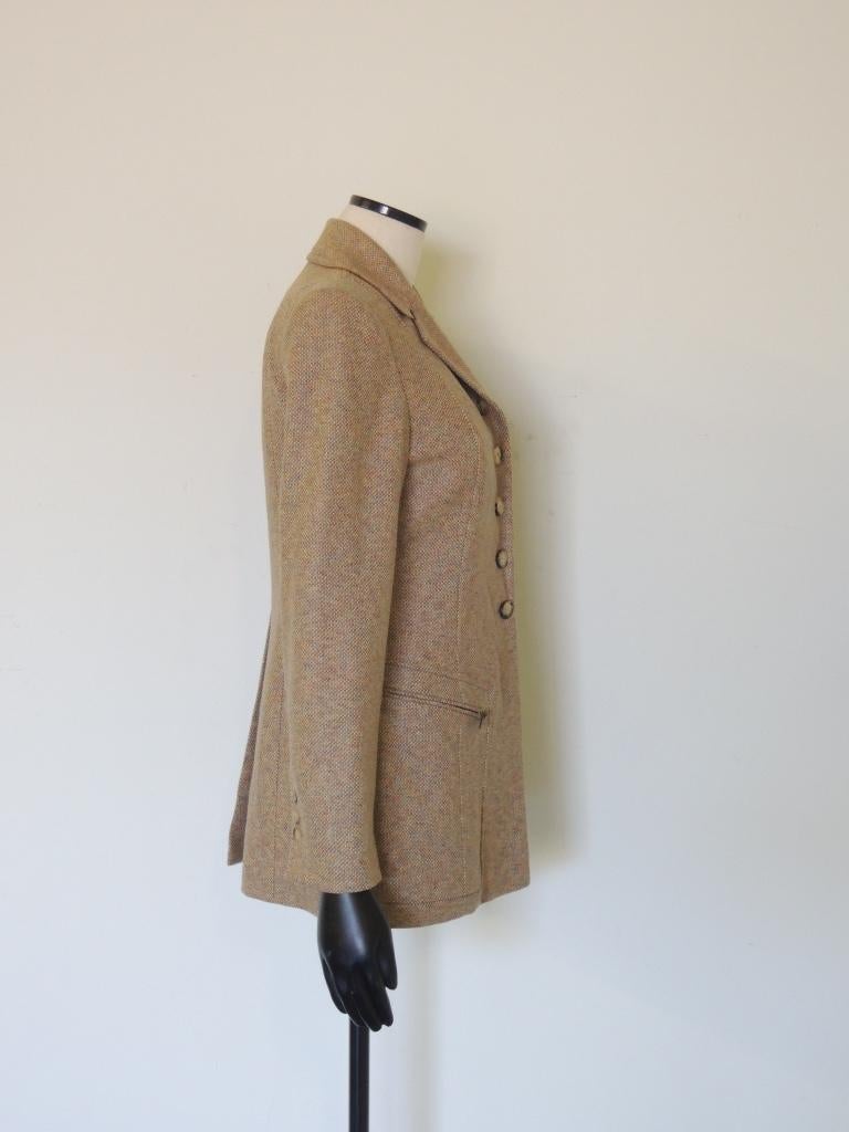 This equestrian-style wool and cashmere tweed jacket from Hermes features a 5-button front with three zippered pockets and leather trim under the functional cuff buttons. Form-fitting with a vented back and notch lapels. The jacket body is composed