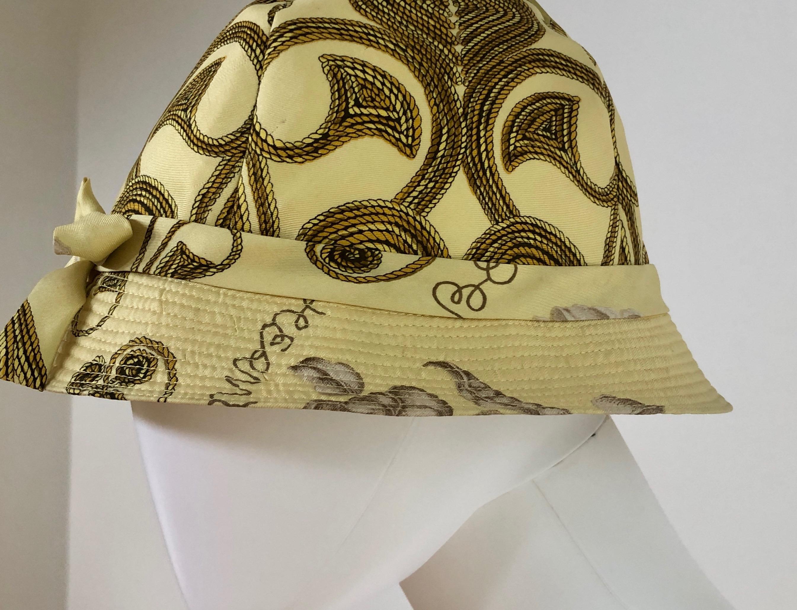 Offered is an Hermes Yellow, Gold and Ivory silk cloche / bucket hat with a dainty bow to the front center and a gold rope and floral theme.

Make:  Hermes (label reads Hermes Paris)
Place of manufacture:  France
Size:  58 (approximating)
Color: 