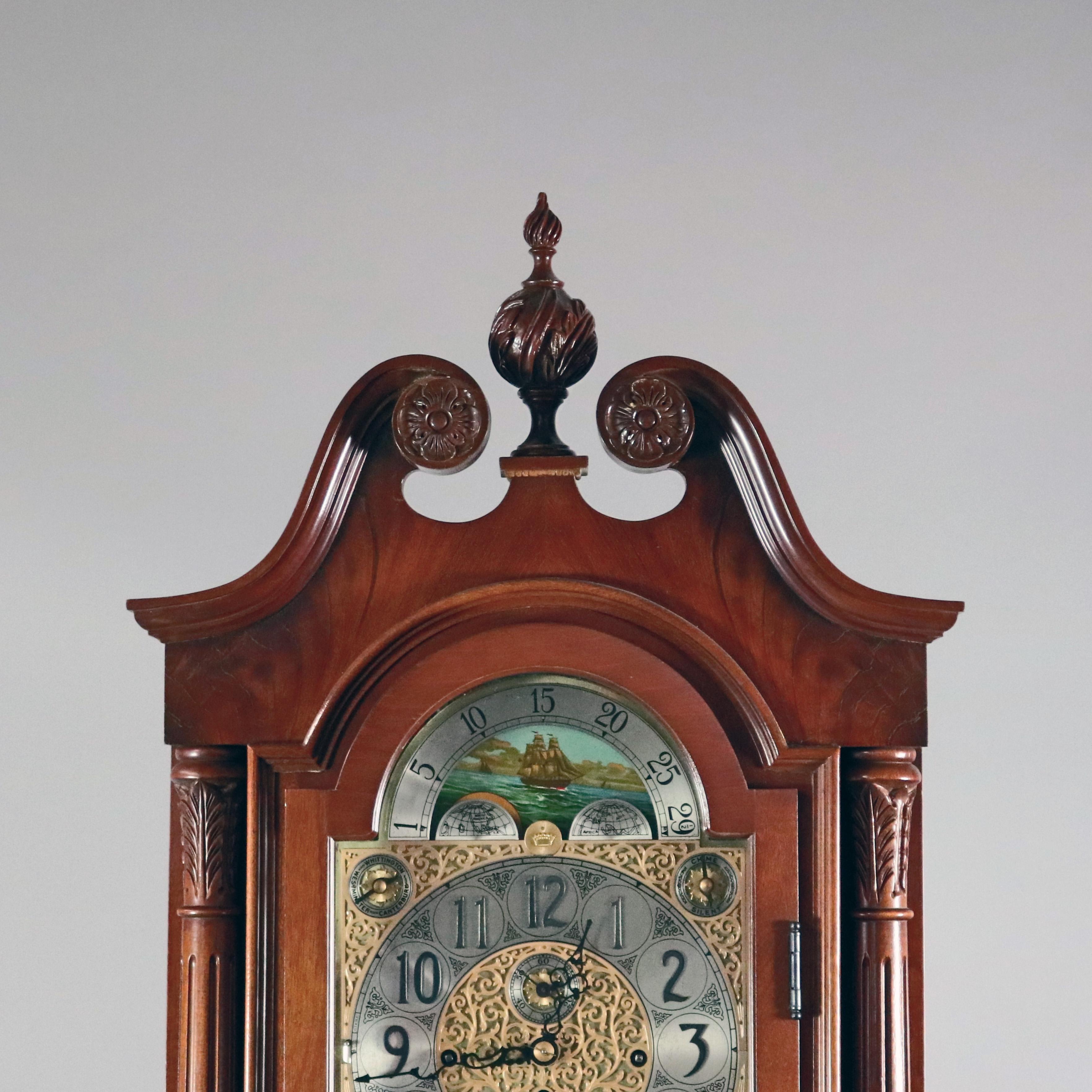 Une horloge de grand-père vintage par Herschede:: avec un boîtier en acajou:: un capuchon avec un arc brisé:: un rouleau et une rosette:: un fleuron sculpté et feuillu:: un cadran de phase de lune avec un visage percé et feuillu:: des chiffres