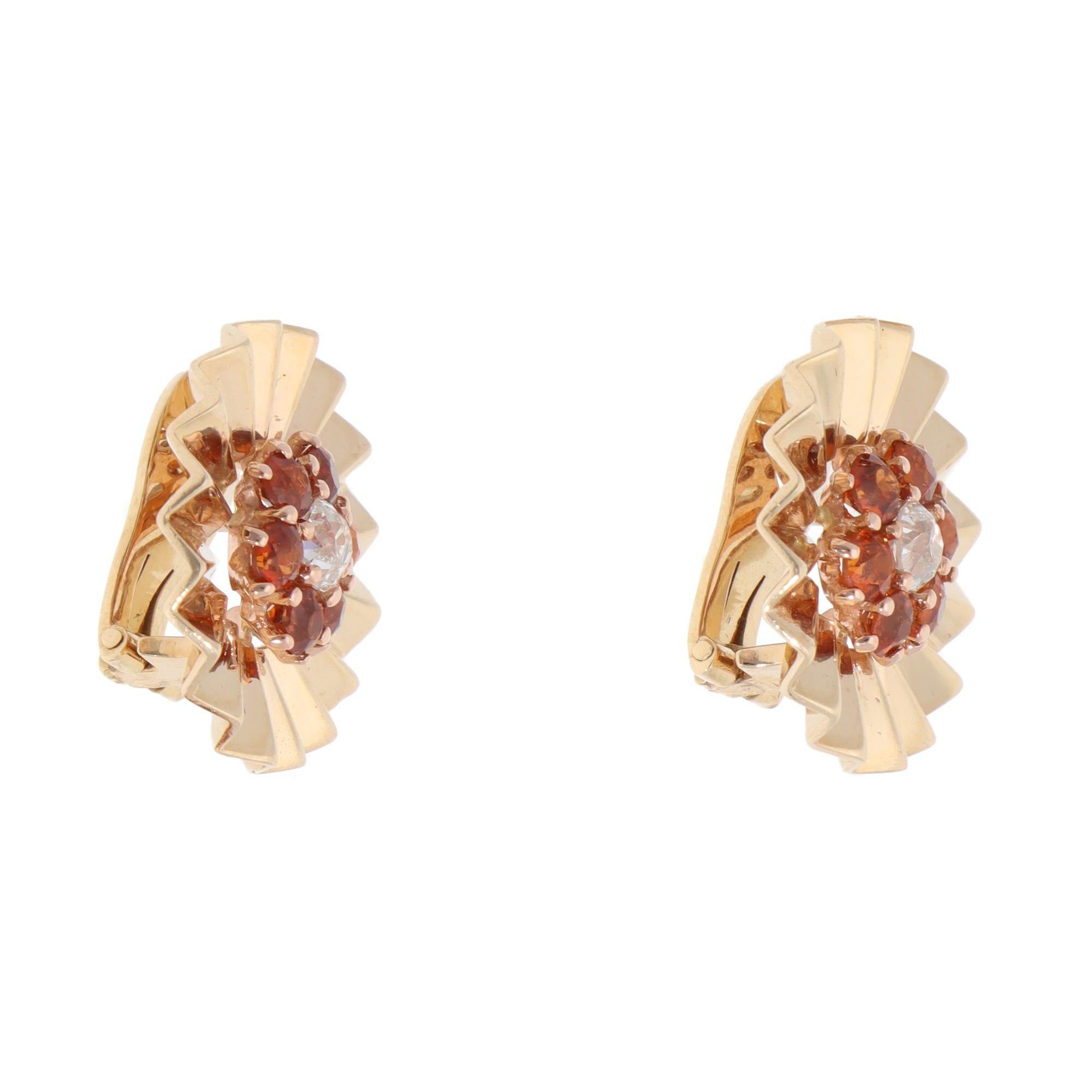 A beautiful pair of vintage hessonite garnet and diamond floral clip earrings set in 14k yellow gold.

Each earring depicts a floral cluster motif centrally set with an old-cut diamond and surrounded by 6 vibrant hessonite garnets. A polished yellow