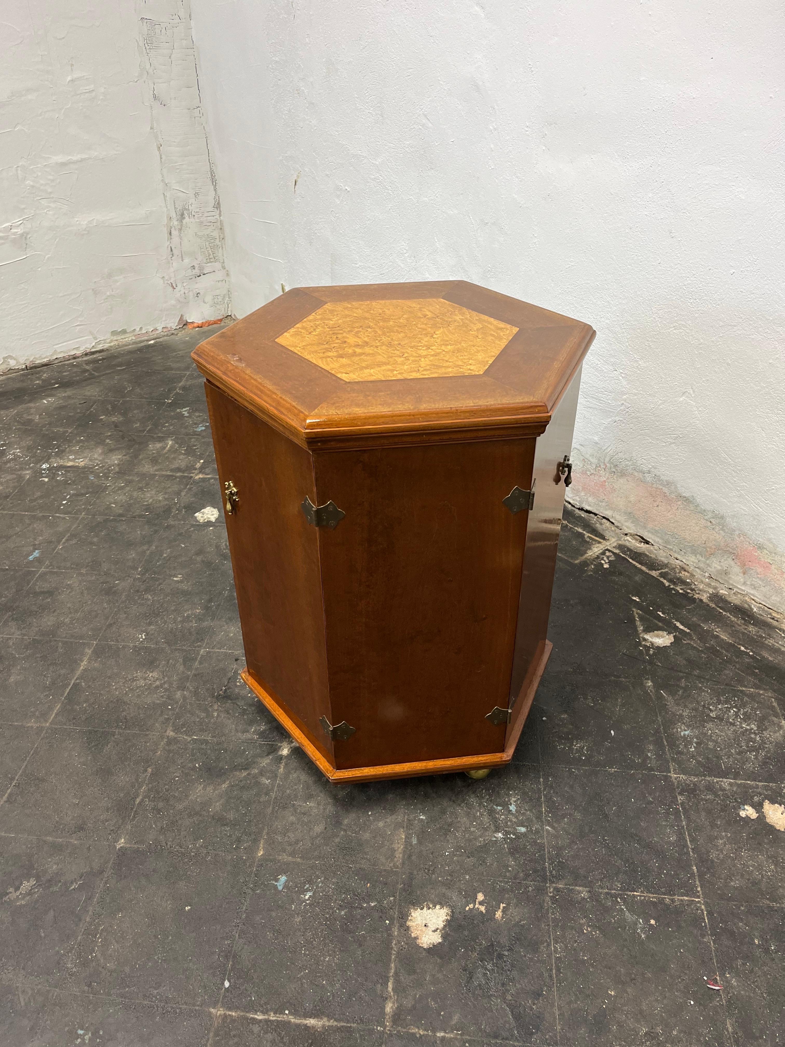 Very unique hexagon table with beautiful burl inset. 3 door with felt lined selves. On compartment has an additional inner shelf. Nicely appointed brass door pulls. Could be a petite game table. On brass casters for ease of placement.
Curbside to