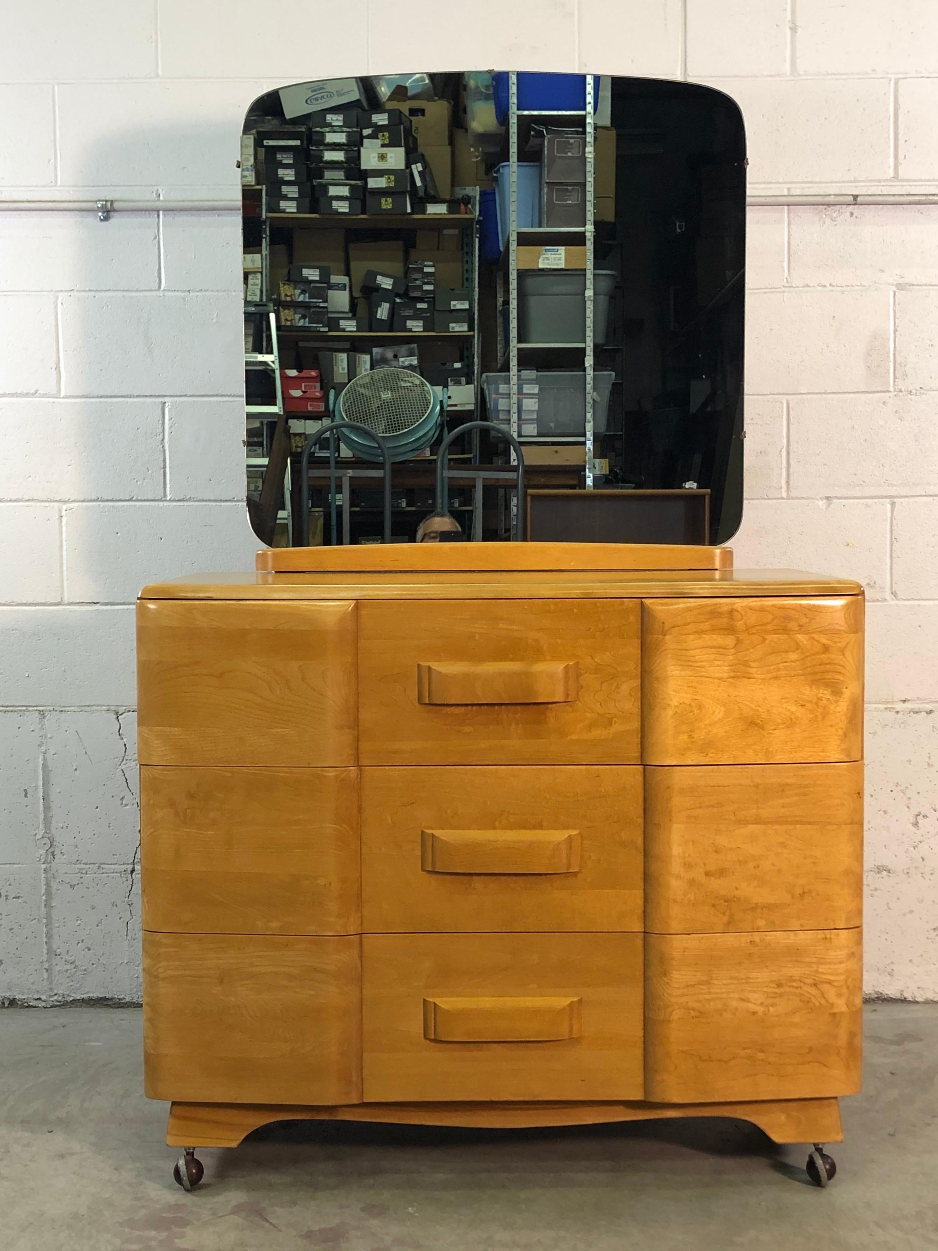 Vintage 1950s Heywood-Wakefield three drawer maple wood dresser with the mirror. The dresser is on casters and rolls freely. The mirror can be detached from the dresser. The dresser height is 35.5”H. Marked. In refinished condition.