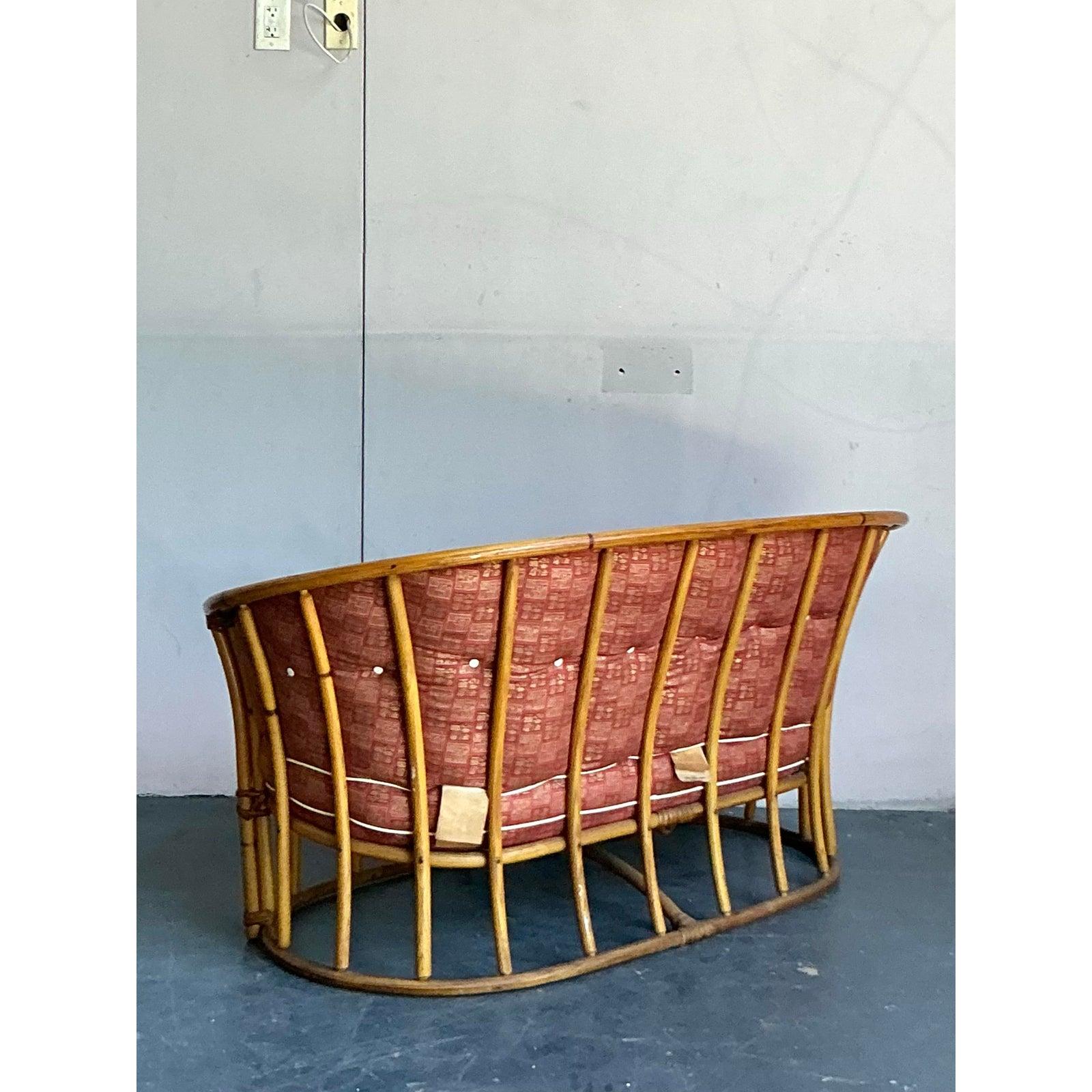 Impresionante ejemplo del ingenio de mediados de siglo, este loveseat de bañera vintage de Heywood Wakefield es una obra maestra de forma y comodidad. Su elegante silueta envolvente con respaldo de tonel está expertamente elaborada con ratán