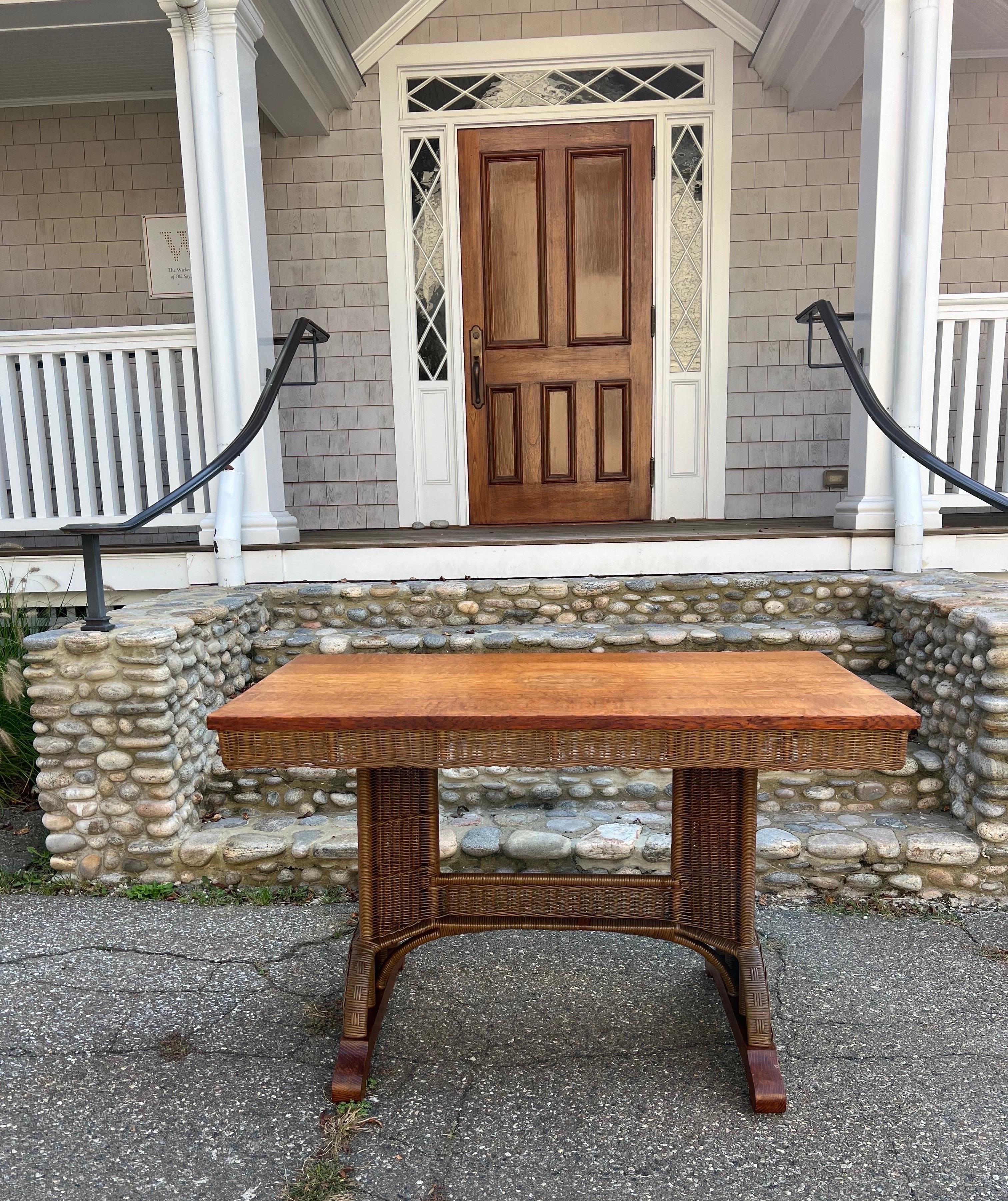 Vintage Heywood Wakefield wicker and oak trestle table. Wood top is made if quarter sawn oak with woven reed skirt. Table sits in oak and wicker base. Table measures 48”x26”x30”tall.  Signs of previous use on table top with light staining.