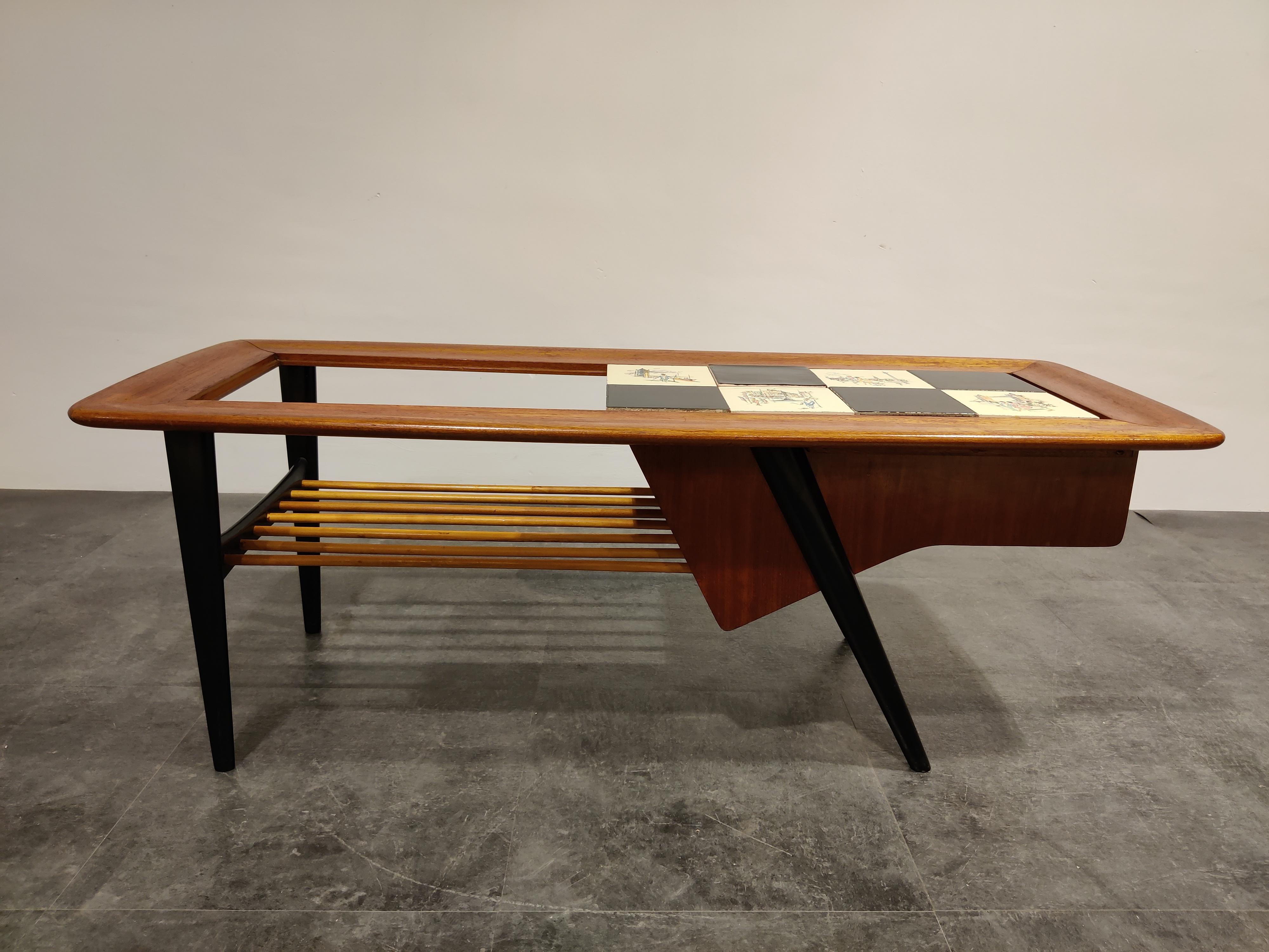 Midcentury coffee table by the Belgian designer Alfred Hendrickx.

The table features a hidden bar compartment and a moveable ceramic tyle top with drawings.

Beautifully finished wooden top and black lacquered legs.

One of our favorite