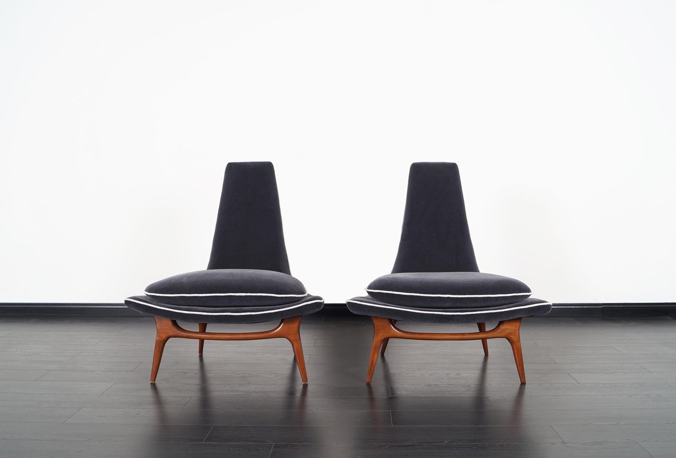 Stunning pair of vintage high back lounge chairs designed by Karpen of California, circa 1950s. These magnificent chairs feature sculpted solid walnut legs that show smooth curves and graceful lines across the frame. They've been professionally