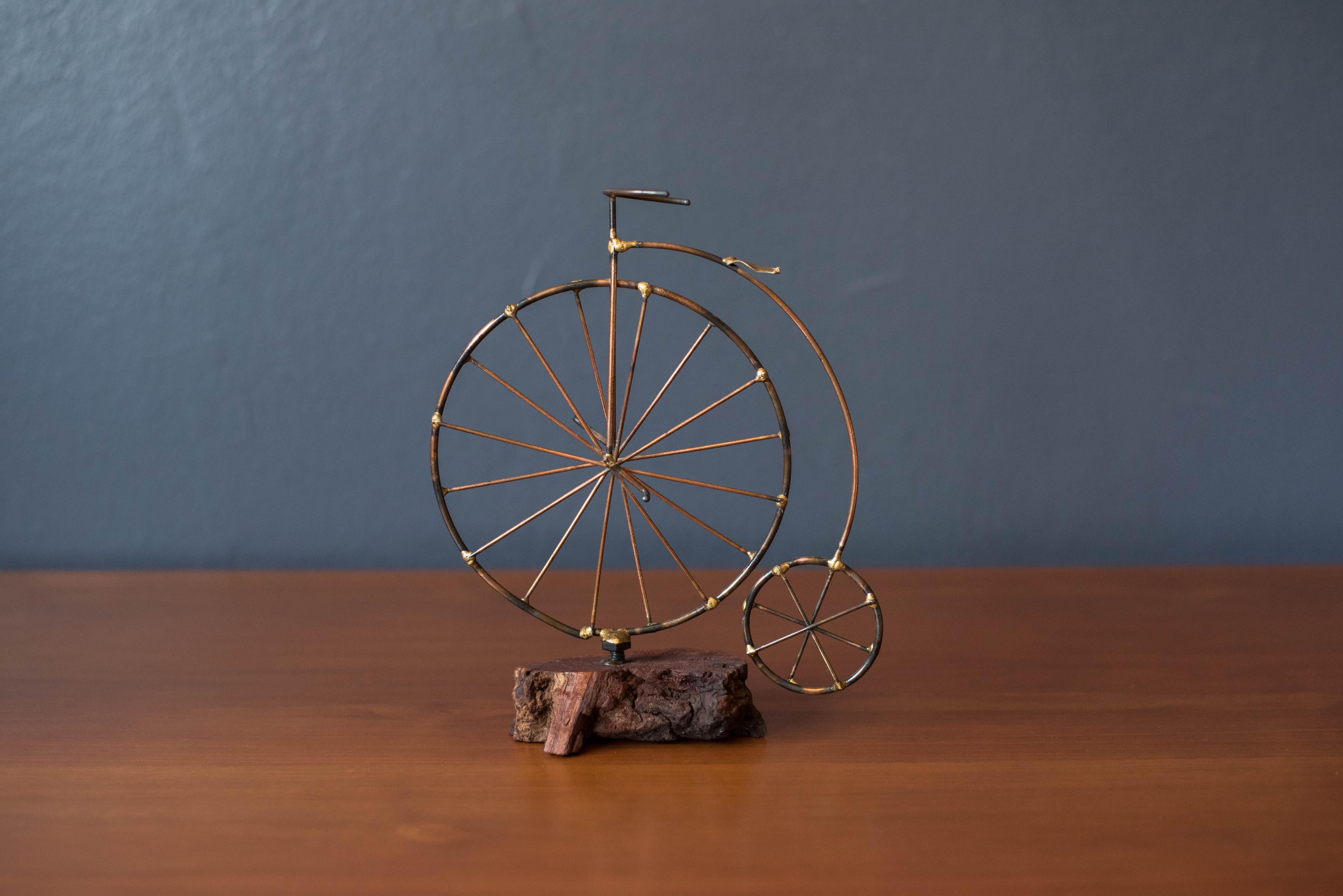 Mid-Century Modern studio art high wheeler bicycle sculpture circa 1970's. This piece is crafted of mixed metals mounted on a free form burl wood base. The perfect accent tabletop or desktop piece to complement mid century and industrial modern