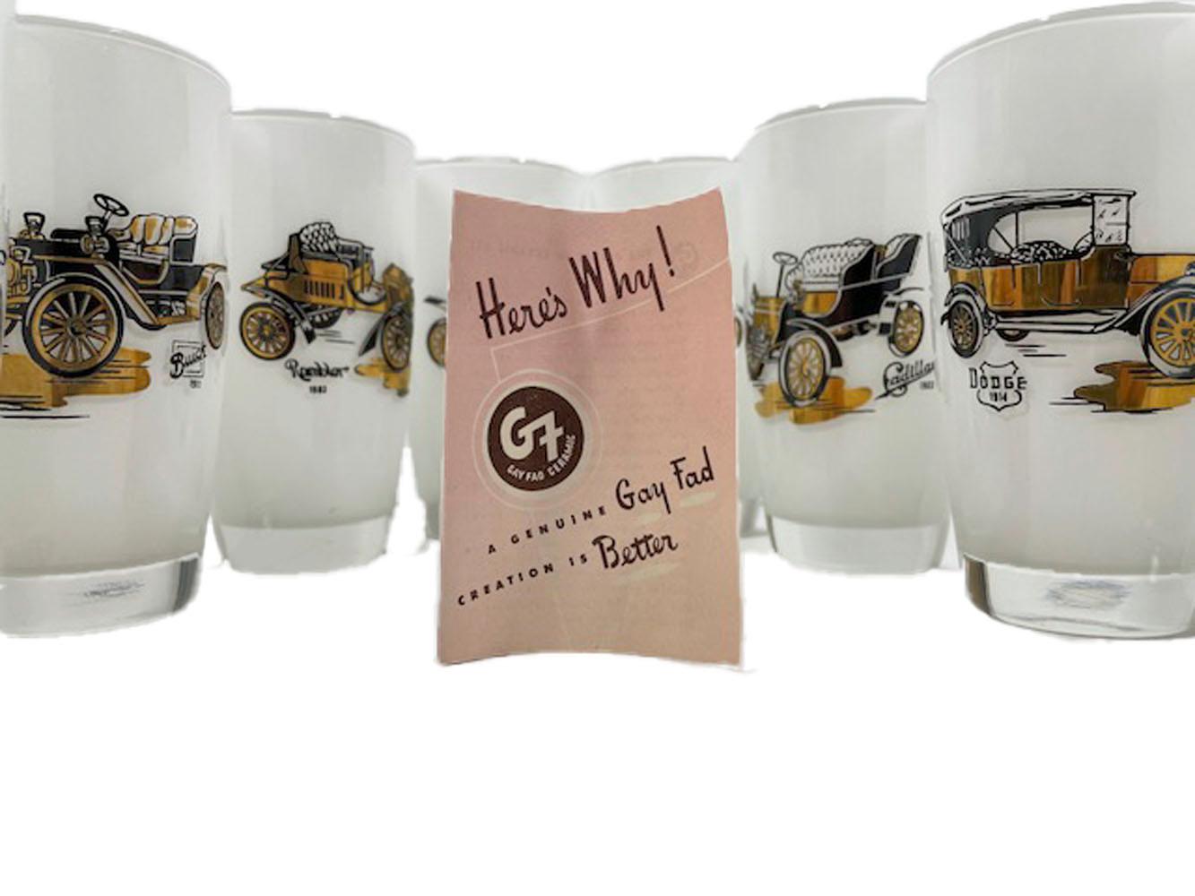 Eight mid-century highball glasses decorated at Fran Taylor's Gay Fad Studio, clear glass with white frosted interior decorated on the exterior with black enamel and 22k gold images of antique automobiles along with a caption identifying the make