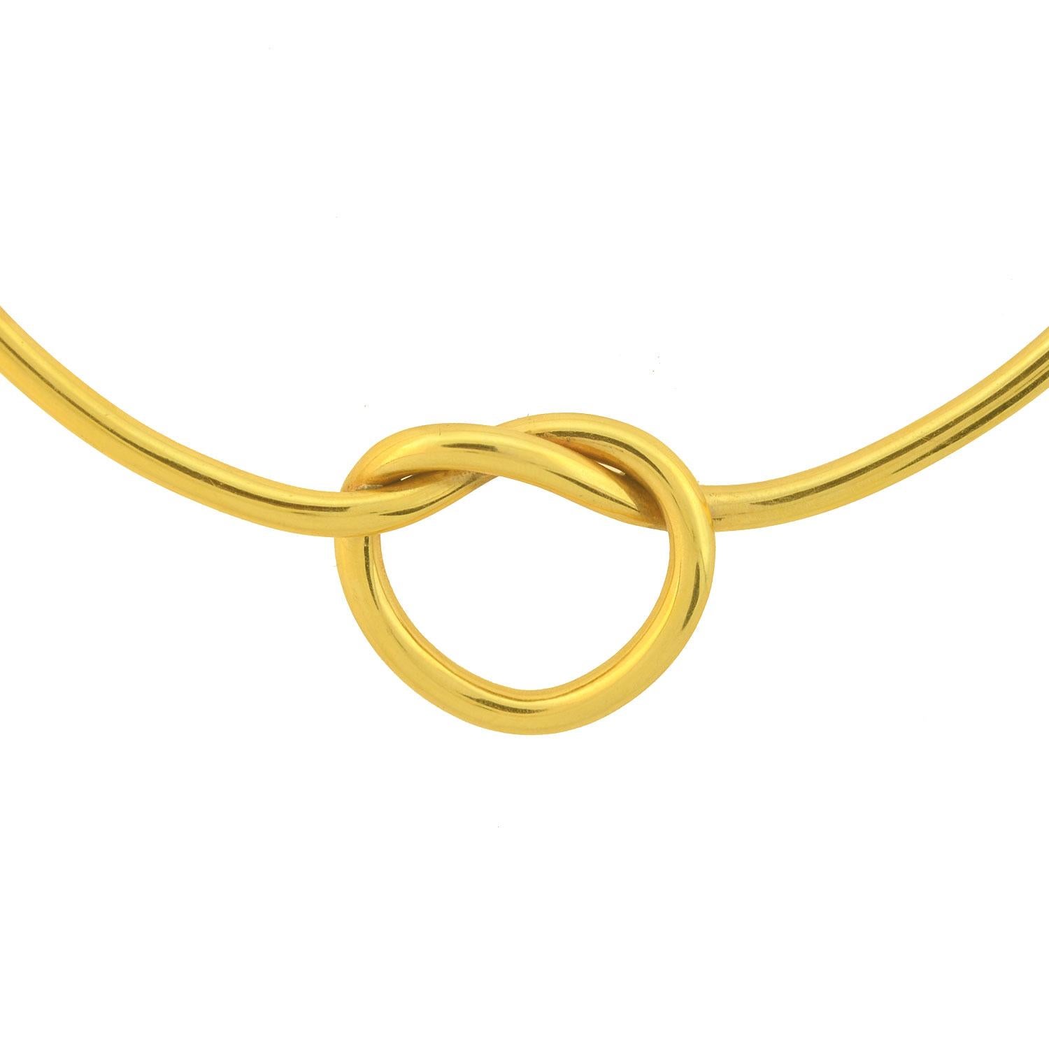 A stunning Vintage necklace from the 1970s! Crafted in 18kt yellow gold, this gorgeous piece has an inflexible collar design and features a large love knot at its center. The polished yellow gold necklace is comprised of a thick, single gold tube,