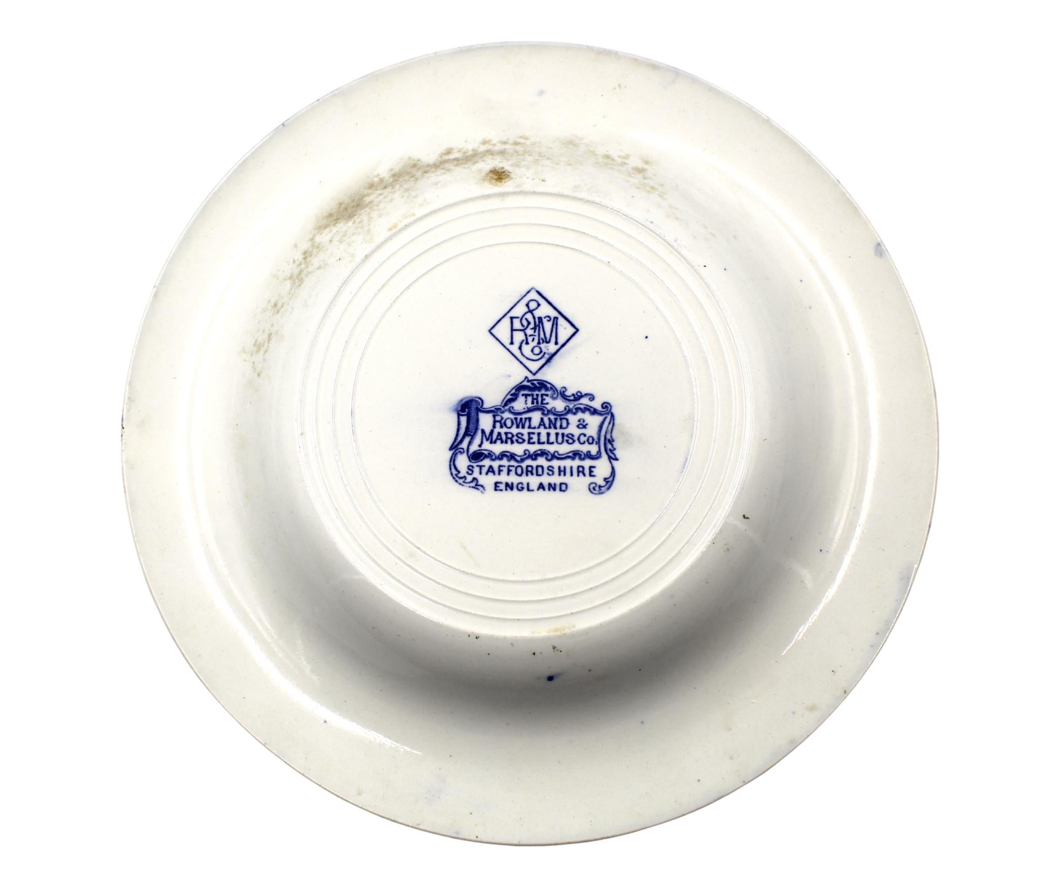 Presented is a blue-glazed transferware plate, by the famous earthenware importers, The Rowland & Marsellus Company.  Made in Staffordshire, England, this plate pattern celebrates historical Philadelphia. The scene depicts Independence Hall at