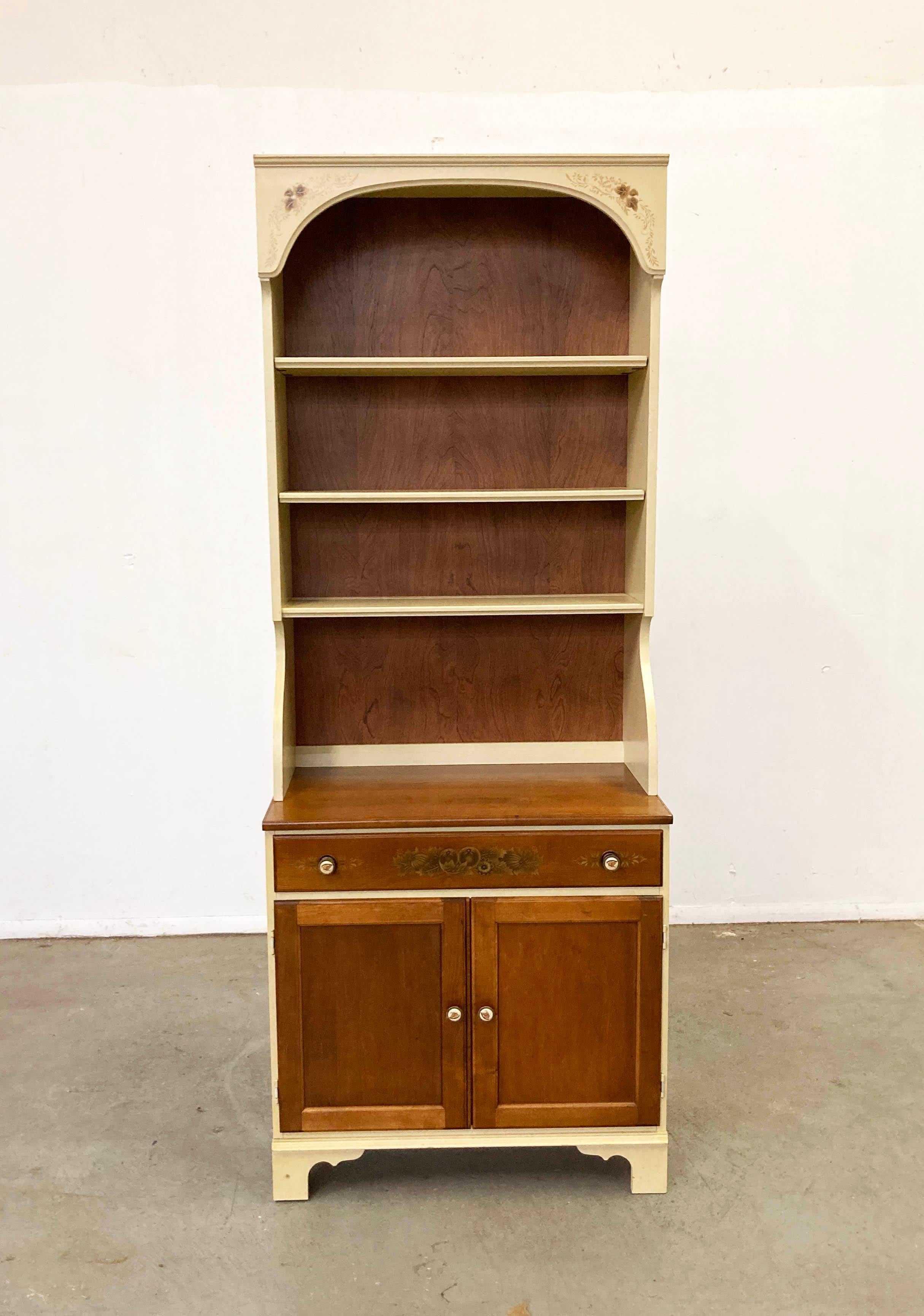 Offered is a vintage two-piece hardwood cherry cabinet/bookshelf made by Lambert Hitchcock. Includes a hutch top with shelving and a bottom cabinet with one top drawer and inner shelving. Features beautiful stenciling and hardware. It is in good