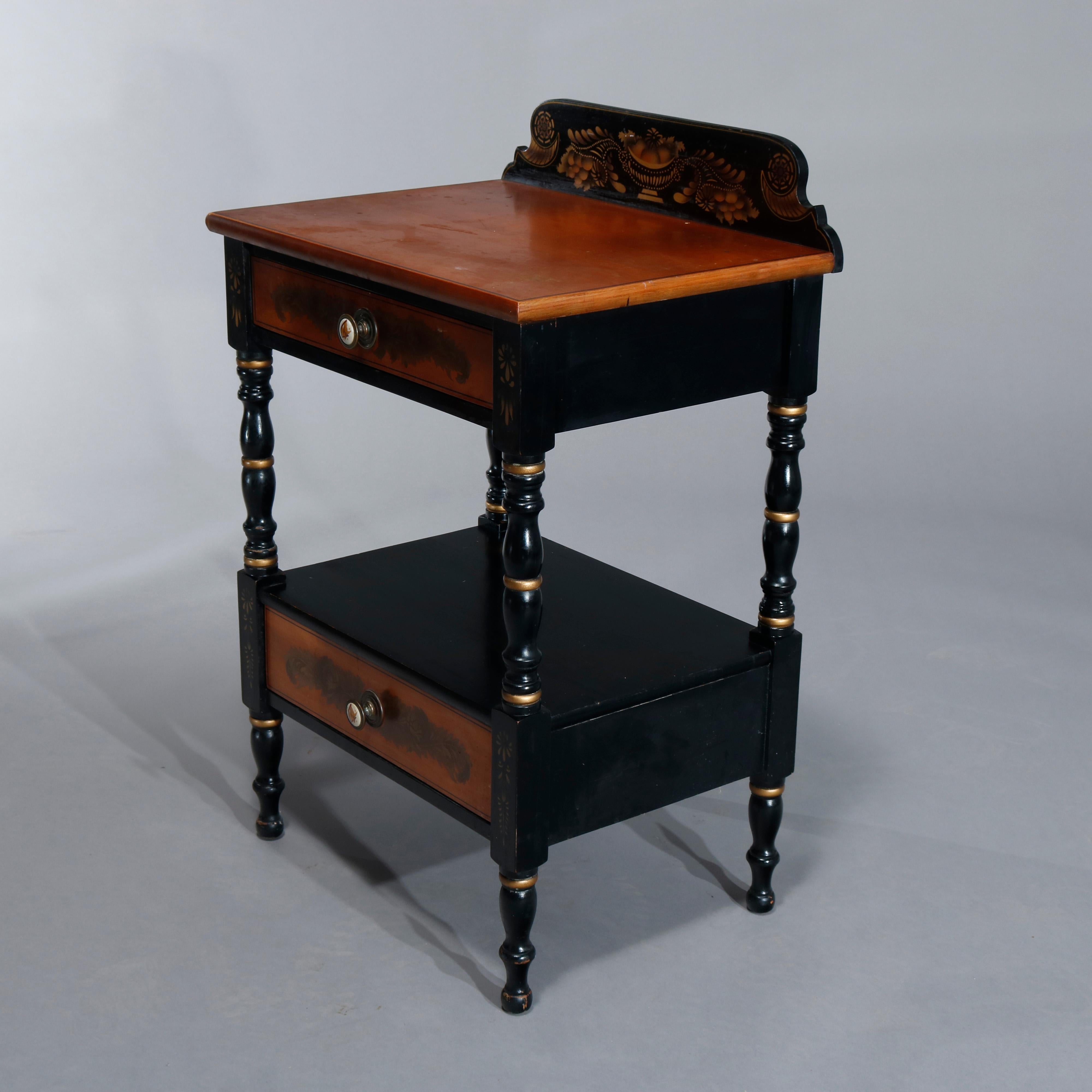 A vintage side stand by Hitchcock offers stenciled backsplash surmounting stand with ebonized frame and having two stenciled drawers, raised on turned legs, gilt banding throughout, en verso signed as photographed, circa 1950.
 
Measures: 31