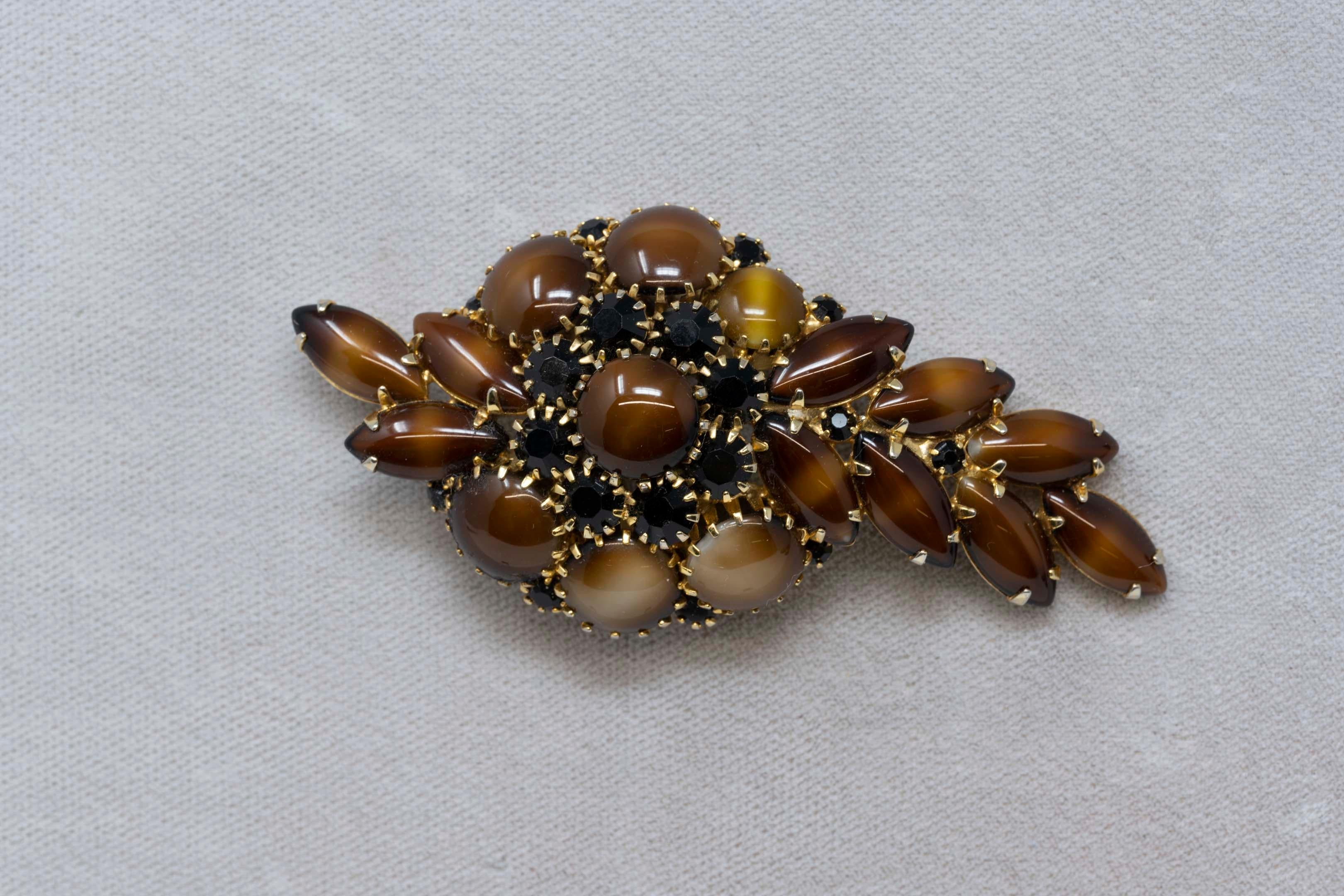 Broche vintage signée Hobe 1965 en or ton sur ton avec cabochon de marbre brun et strass noir. Mesure 3 1/4 pouces de long x 1 1/2 pouces de large. En bon état.
