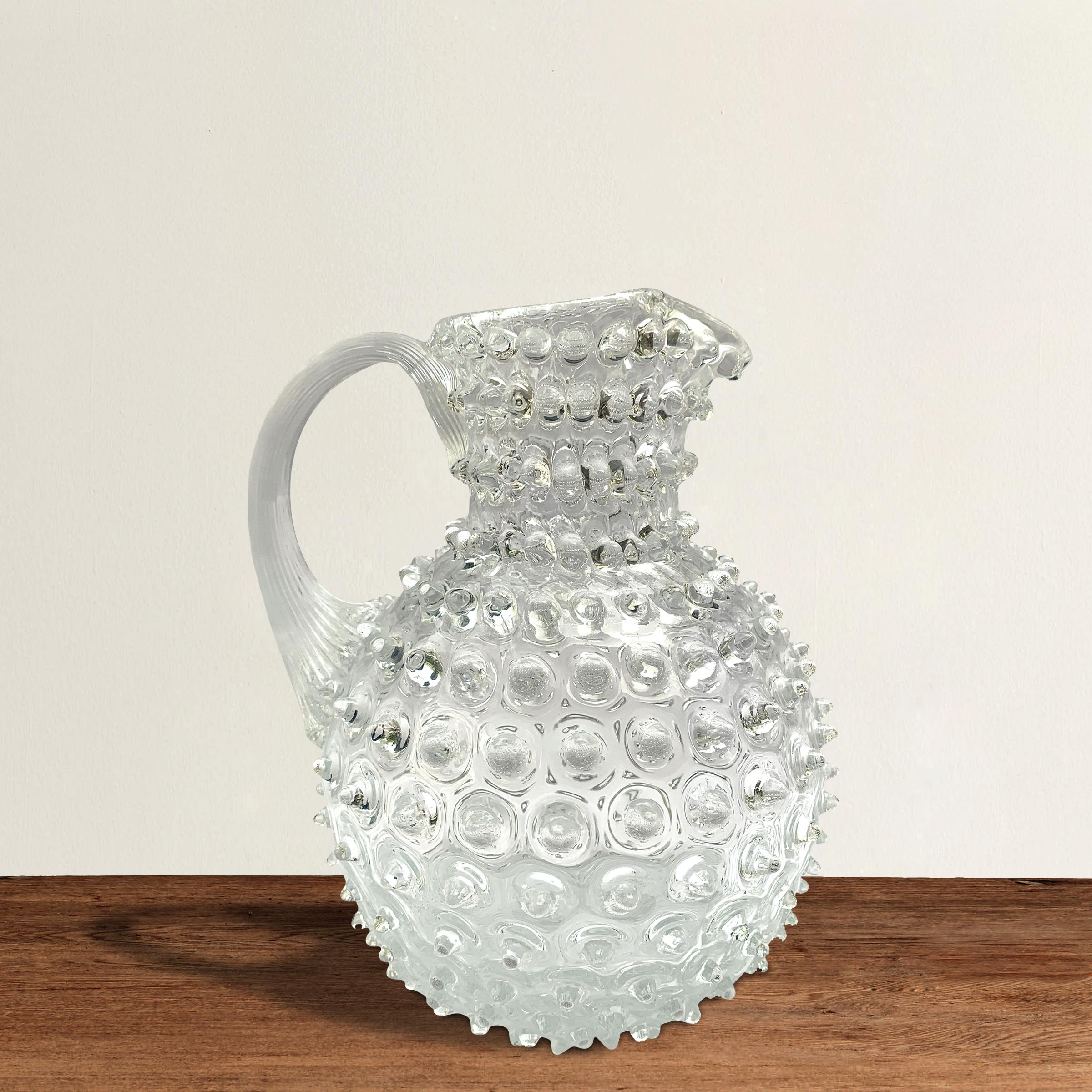 A beautiful vintage hand blown glass pitcher with hundreds of hobnails covering the surface, and a pulled applied handle.