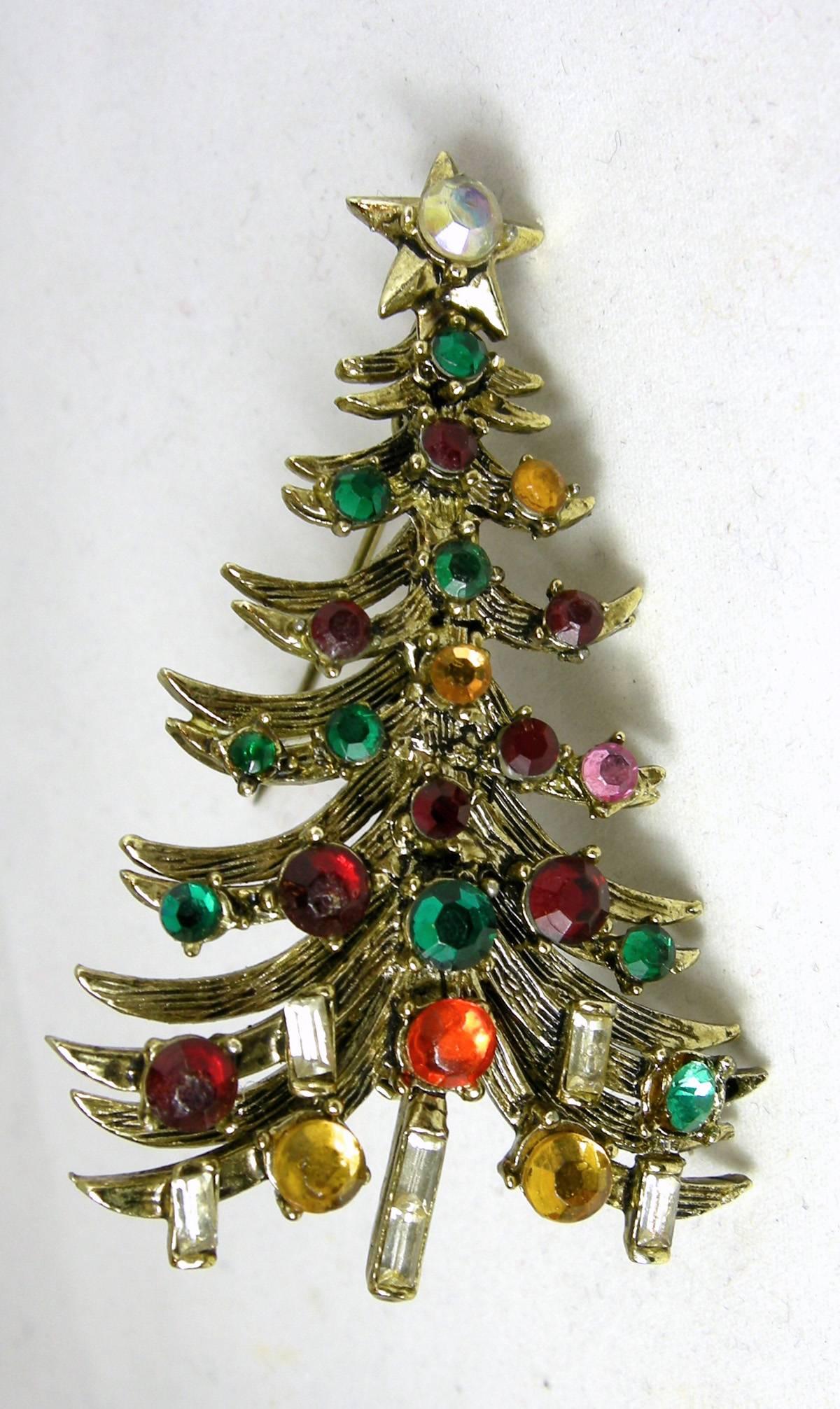 It is very rare to find both the Hollycraft Christmas tree pin with its matching clip earrings, here they are.  The set has multi-color rhinestones with the candles on the bottom…all in Hollycraft’s antique gold tone finish.  The tree is 2-3/4” long