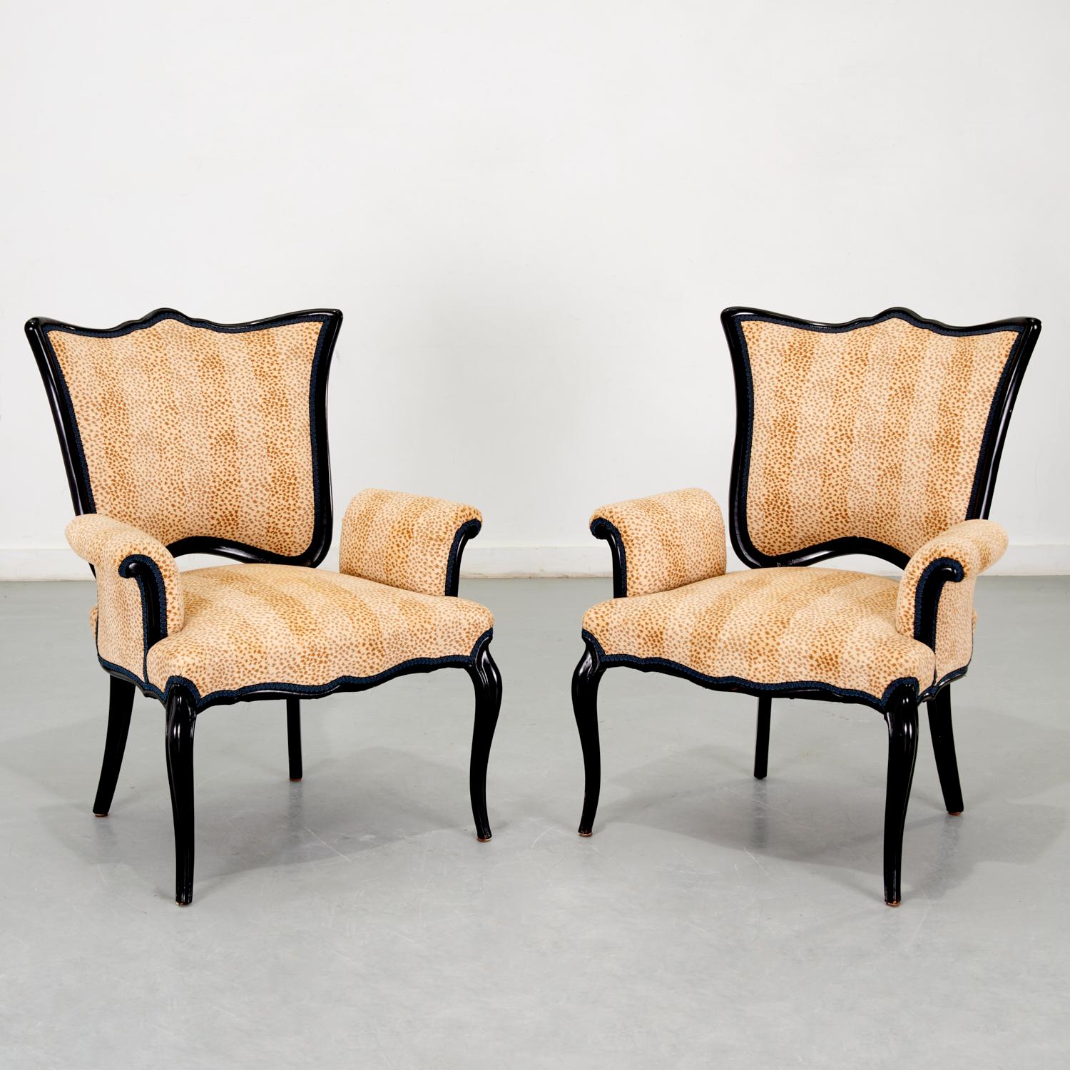 20th c., a pair of Hollywood Regency black lacquer armchairs with cotton velvet cheetah print upholstery accented with French navy braided trim. The chairs are larger than standard chairs of this type which works beautifully with the sinuous curves