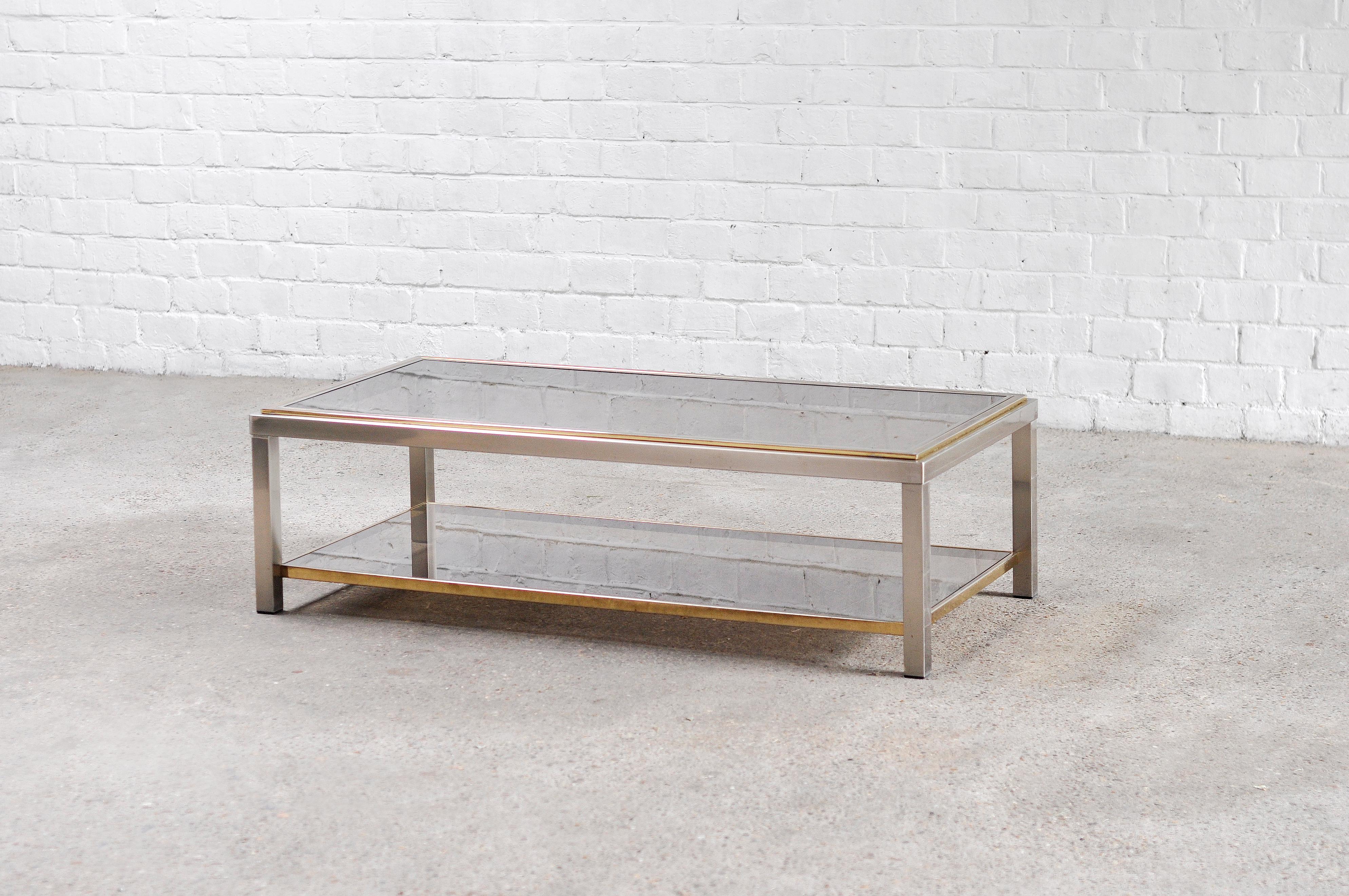 A chic two-tier coffee table in chromed metal with solid brass details and smoked glass shelves. Model 'Flaminia'. The two tier setup is great for displaying books or other objects.
In good vintage condition, with normal signs of age and use.