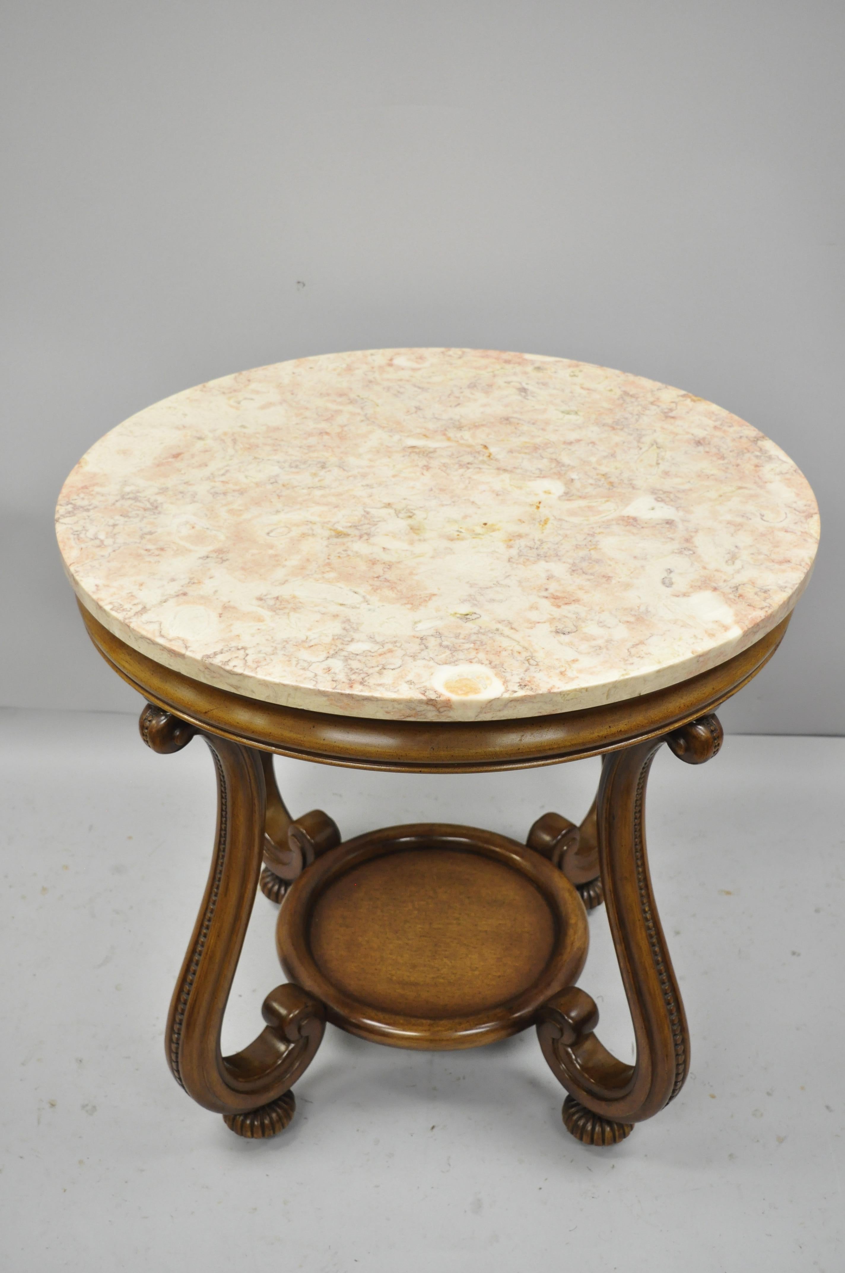 Vintage Hollywood Regency French style pink marble-top round side table. Item features solid mahogany base, lower shelf, rollings casters, pink marble top, circa 1950. Measurements: 27