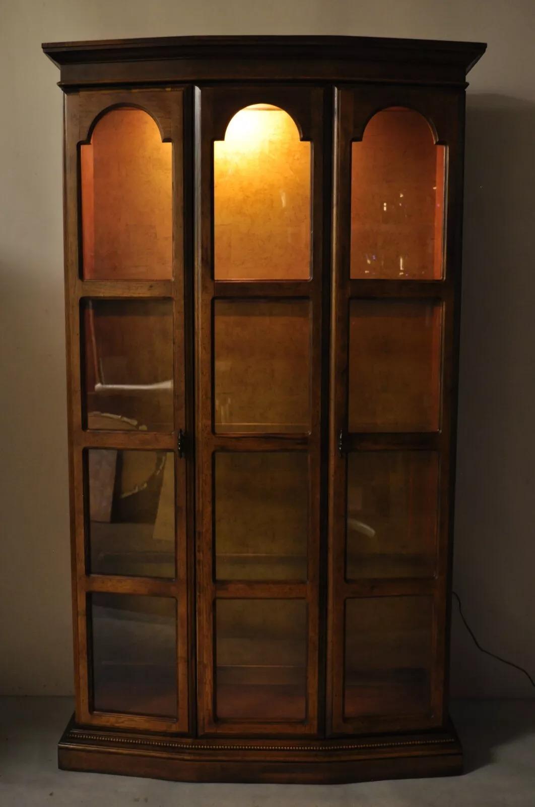Vintage Hollywood Regency Fruitwood Arched 2 Door Glass Tall Curio China Cabinet with 3 Glass Shelves (not adjustable), Gold Backing, and Lighted Interior. ***Listing is for (1) Cabinet. Currently (2) Available***. Circa Late 20th Century.