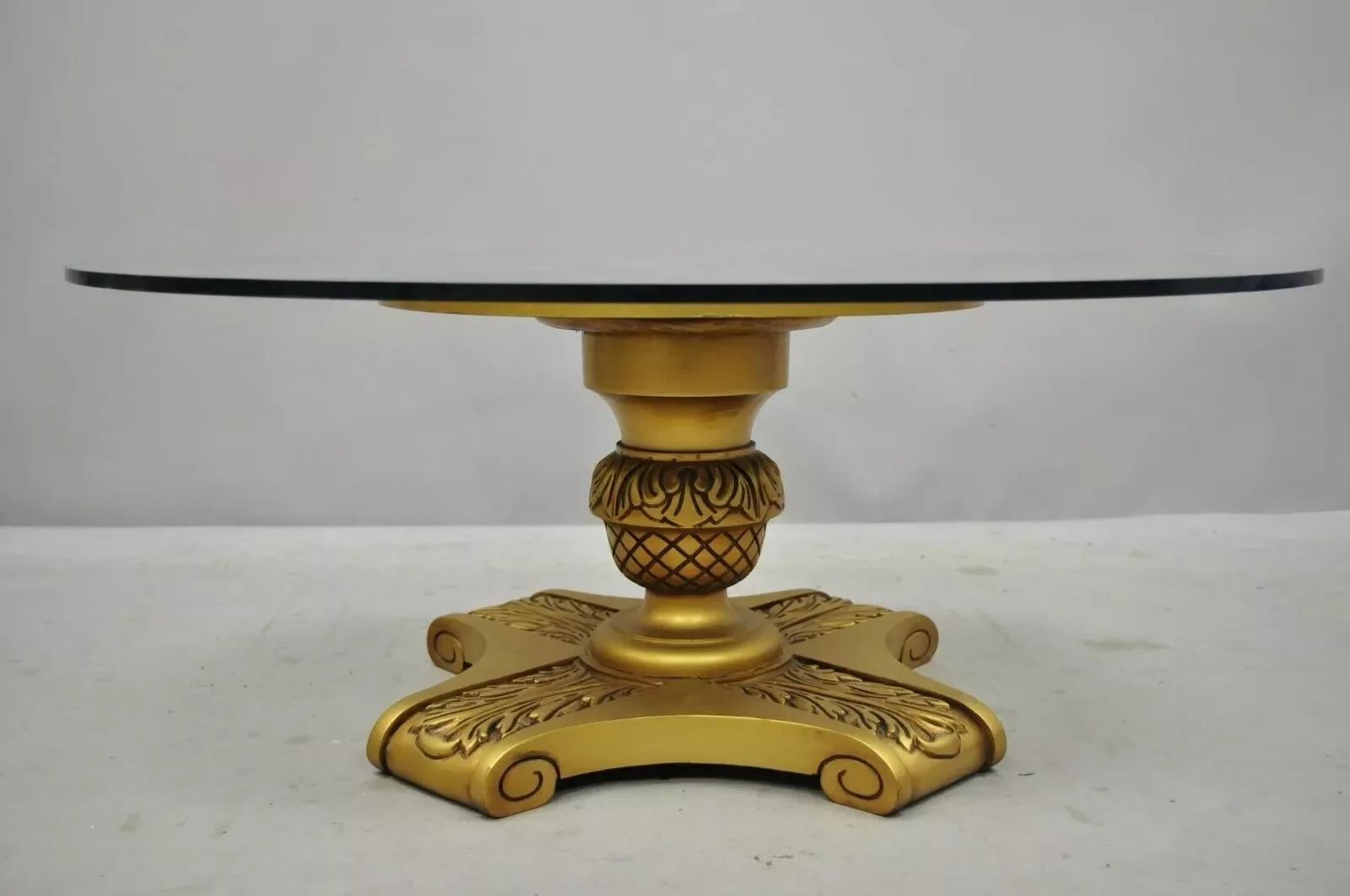 Table à café vintage Hollywood Regency en bois doré avec base à piédestal et plateau de verre rond. Cet article se caractérise par un socle en bois massif sculpté, une finition dorée, un plateau rond en verre, un style et une forme remarquables.